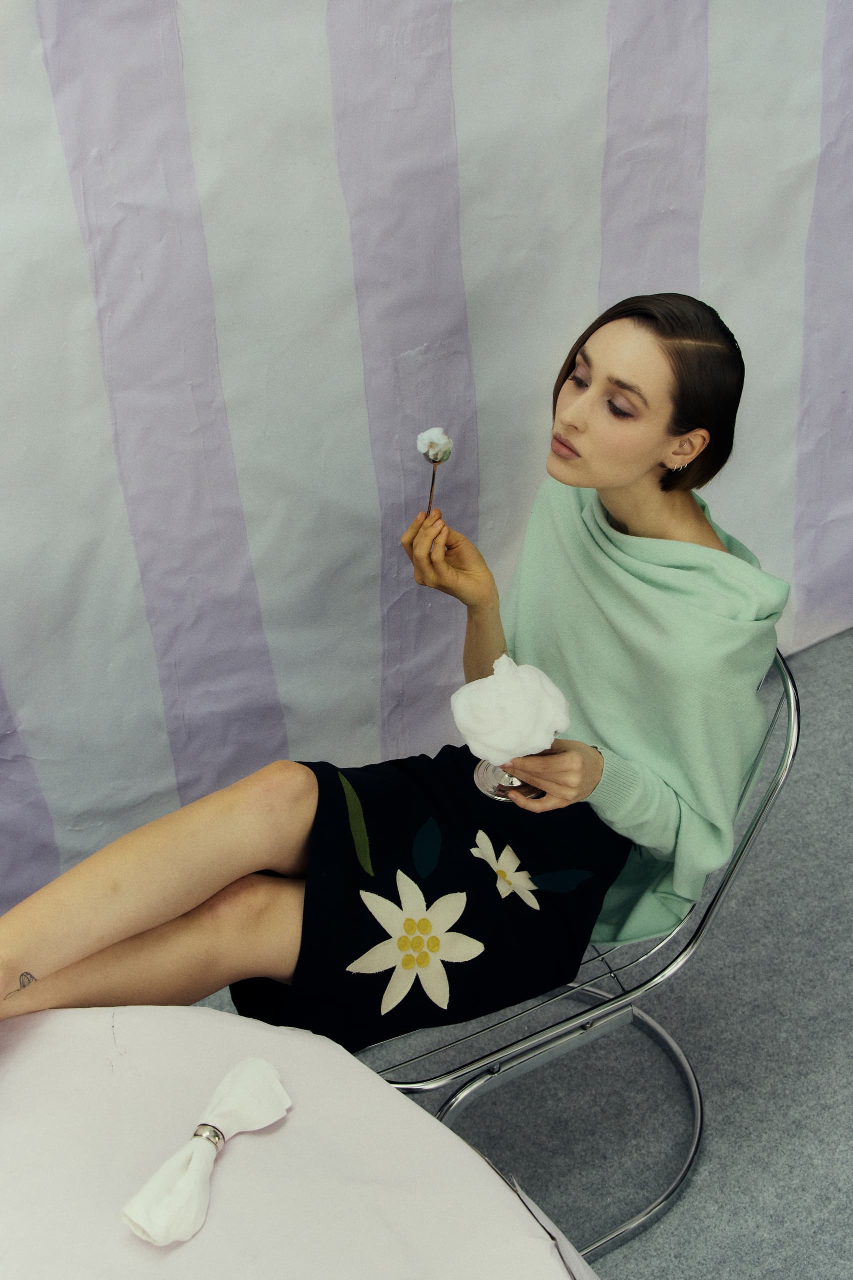 Woman in stylish outfit holding cotton, artistic indoor setting.