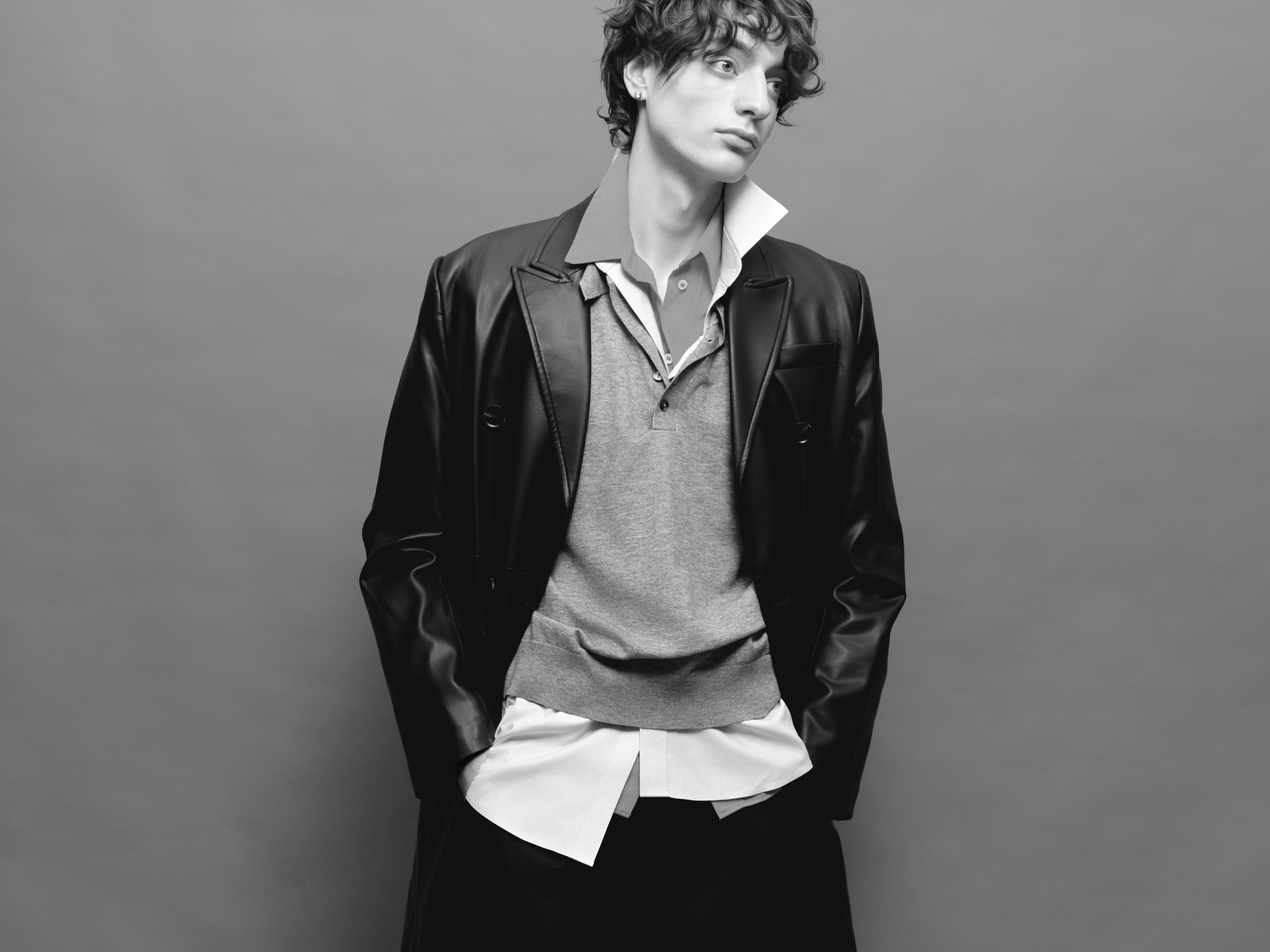 Stylish person in layered clothing and leather jacket, black and white portrait.