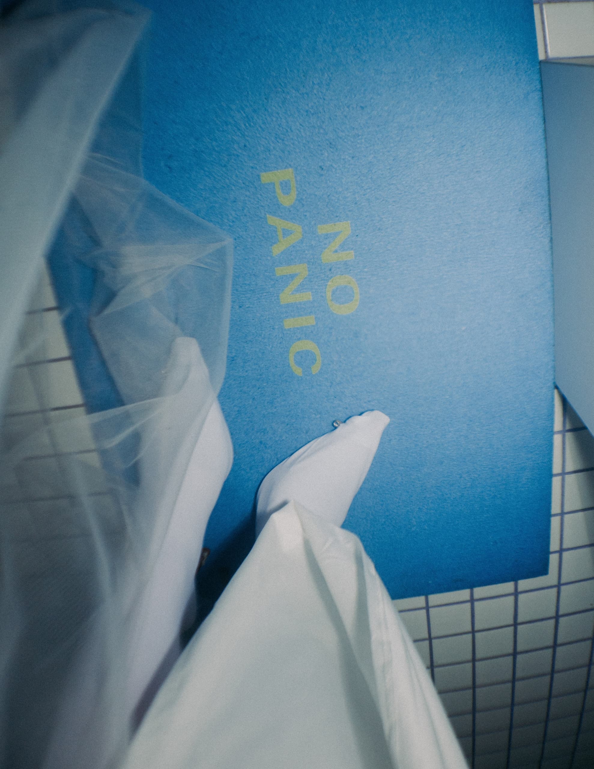 Feet in white fabric on a blue mat with NO PANIC text, calming message.