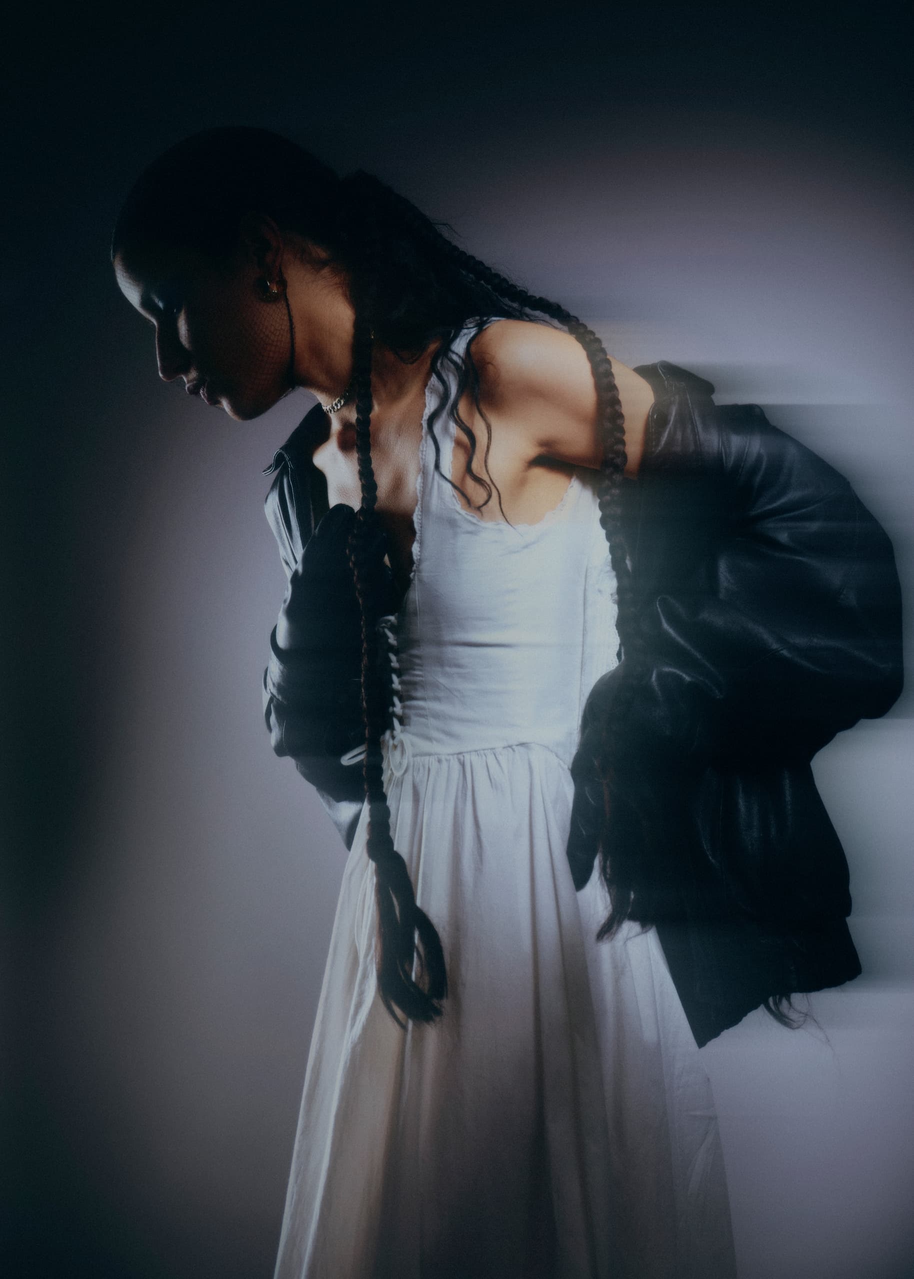 Stylish woman in a flowing dress and leather jacket with dramatic lighting.