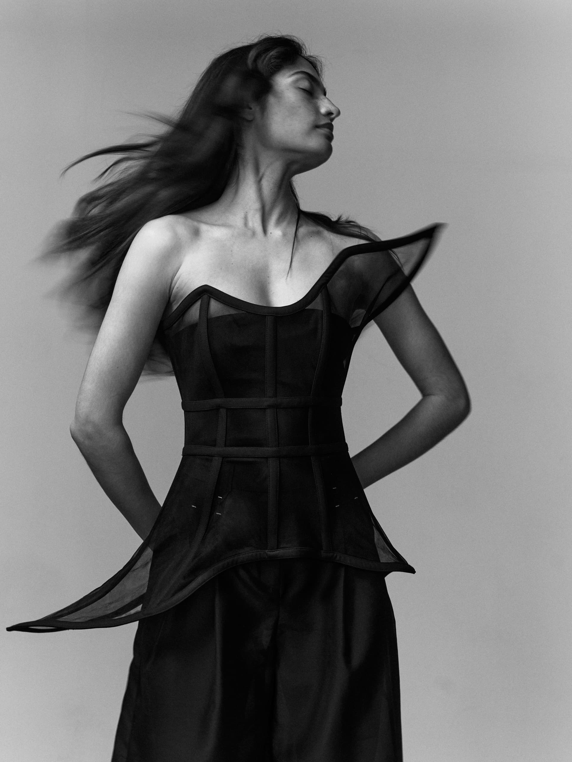 Black and white portrait of woman in stylish, modern dress, with flowing hair.
