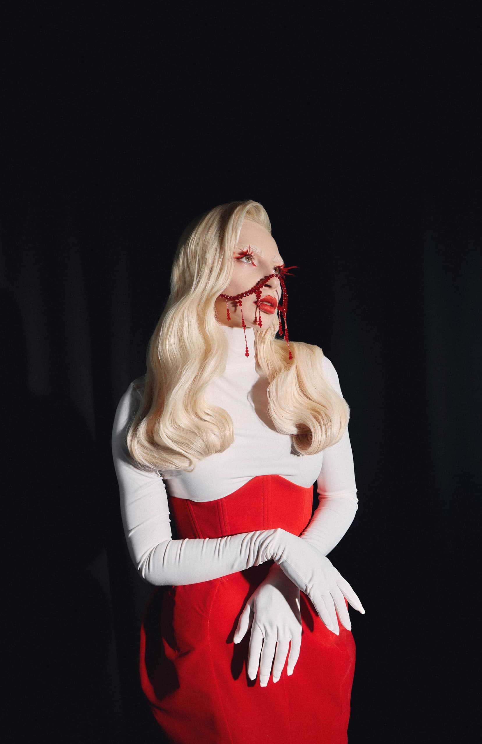 Glamorous fashion model in white and red with dramatic makeup and accessories.