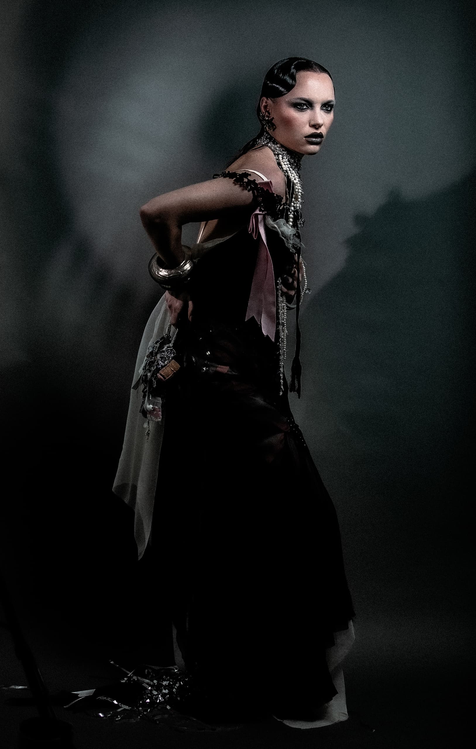 Fashion model in avant-garde attire with dramatic lighting.
