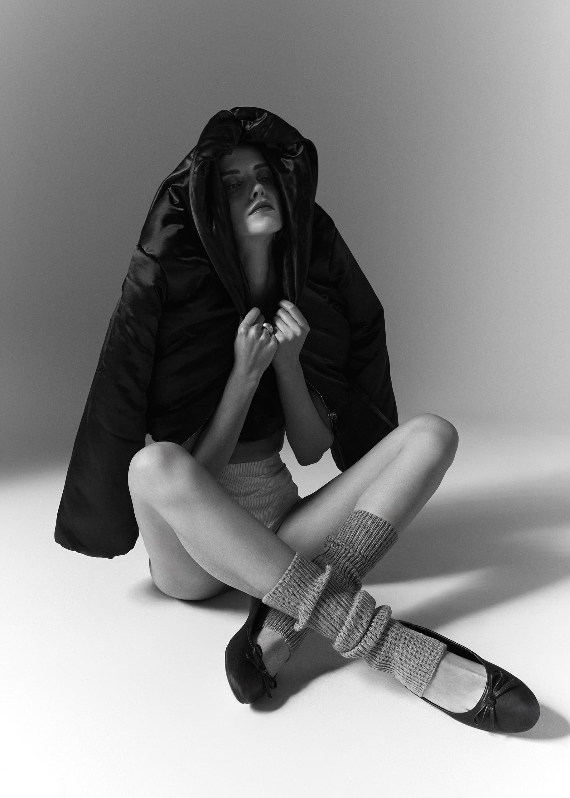 Fashion-forward woman in ballet flats and cozy layers, sitting stylishly.