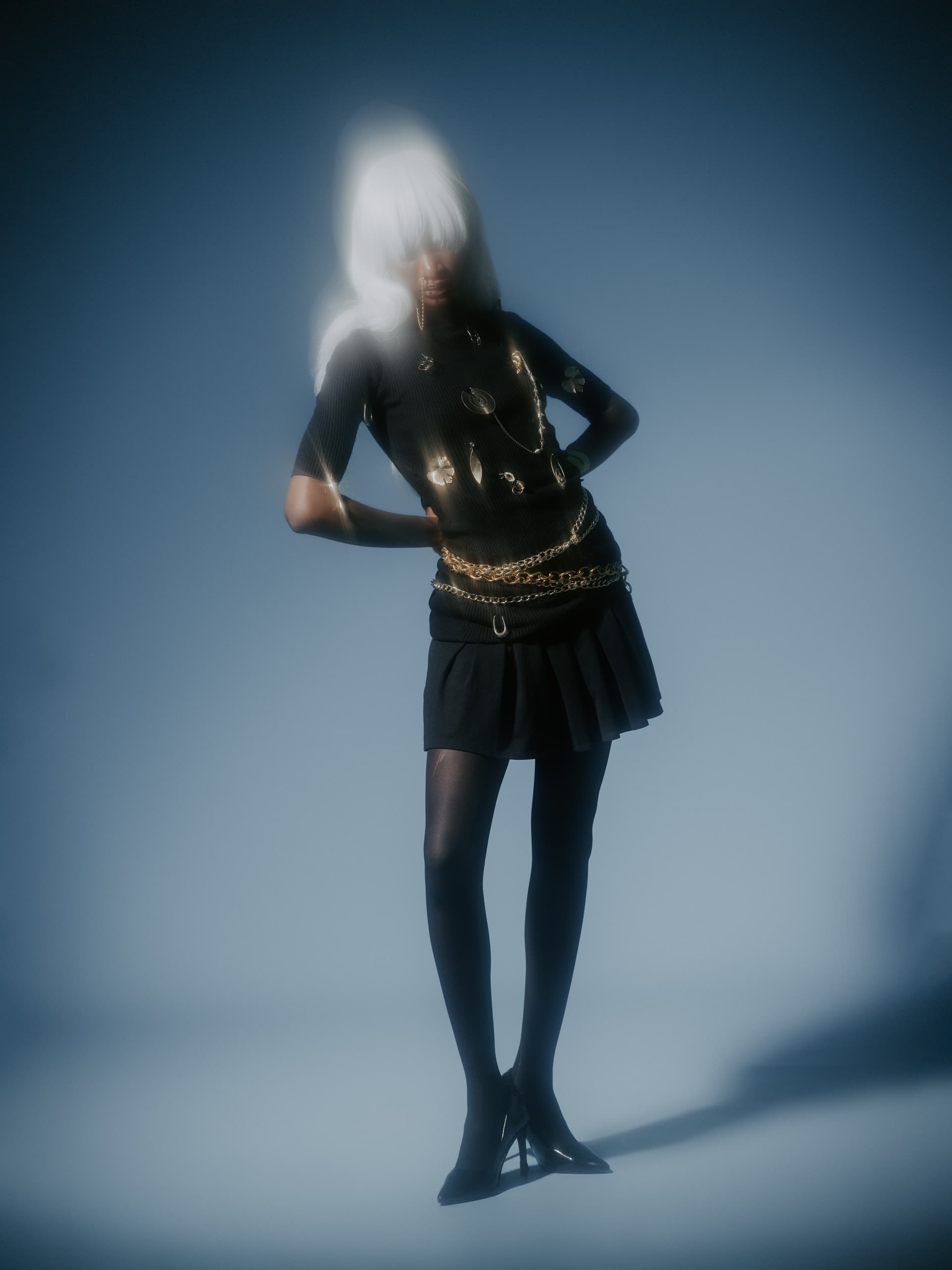 Futuristic fashion photoshoot with model in black outfit and silver accessories.