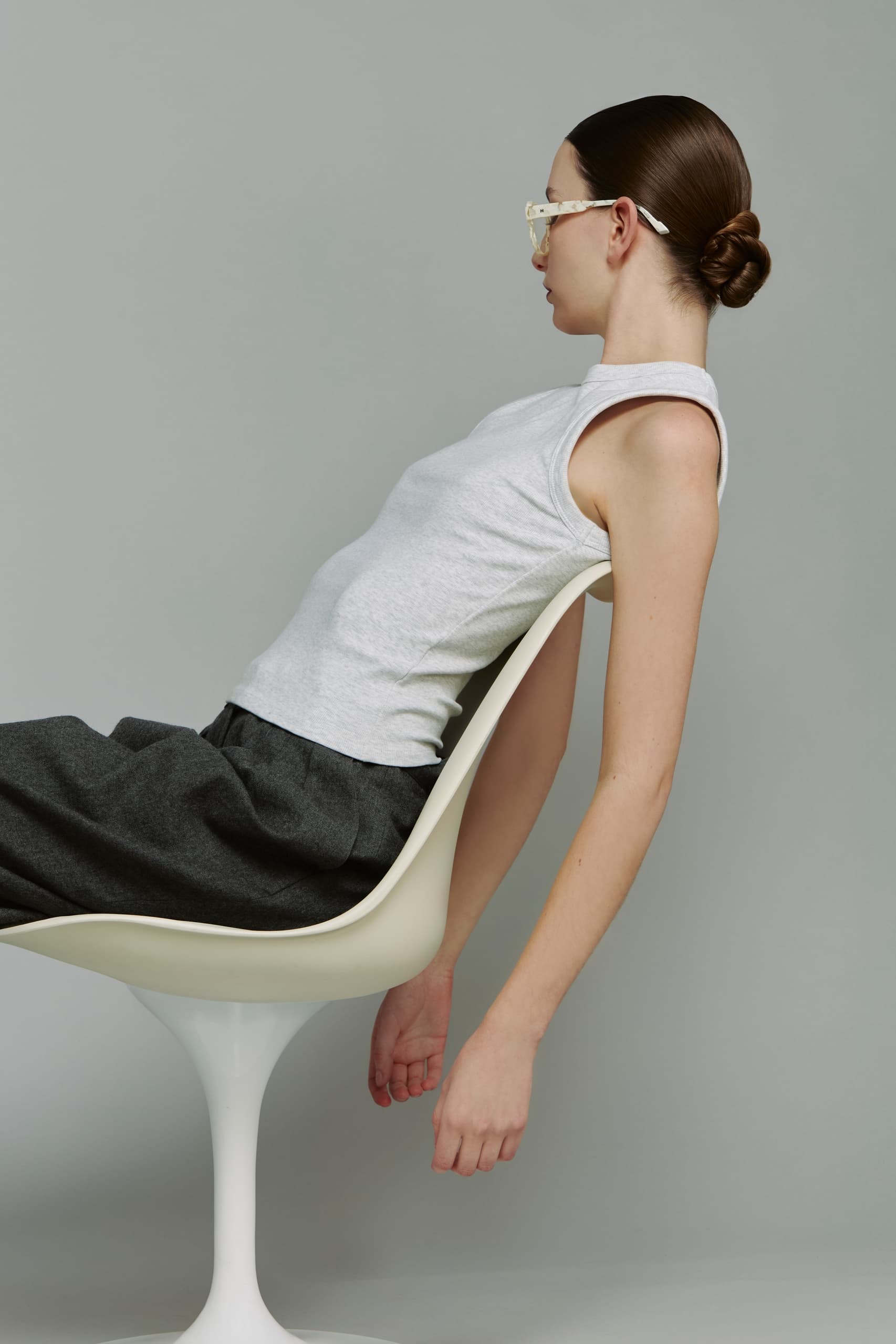 Stylish woman leans back in chair wearing sunglasses and casual outfit.