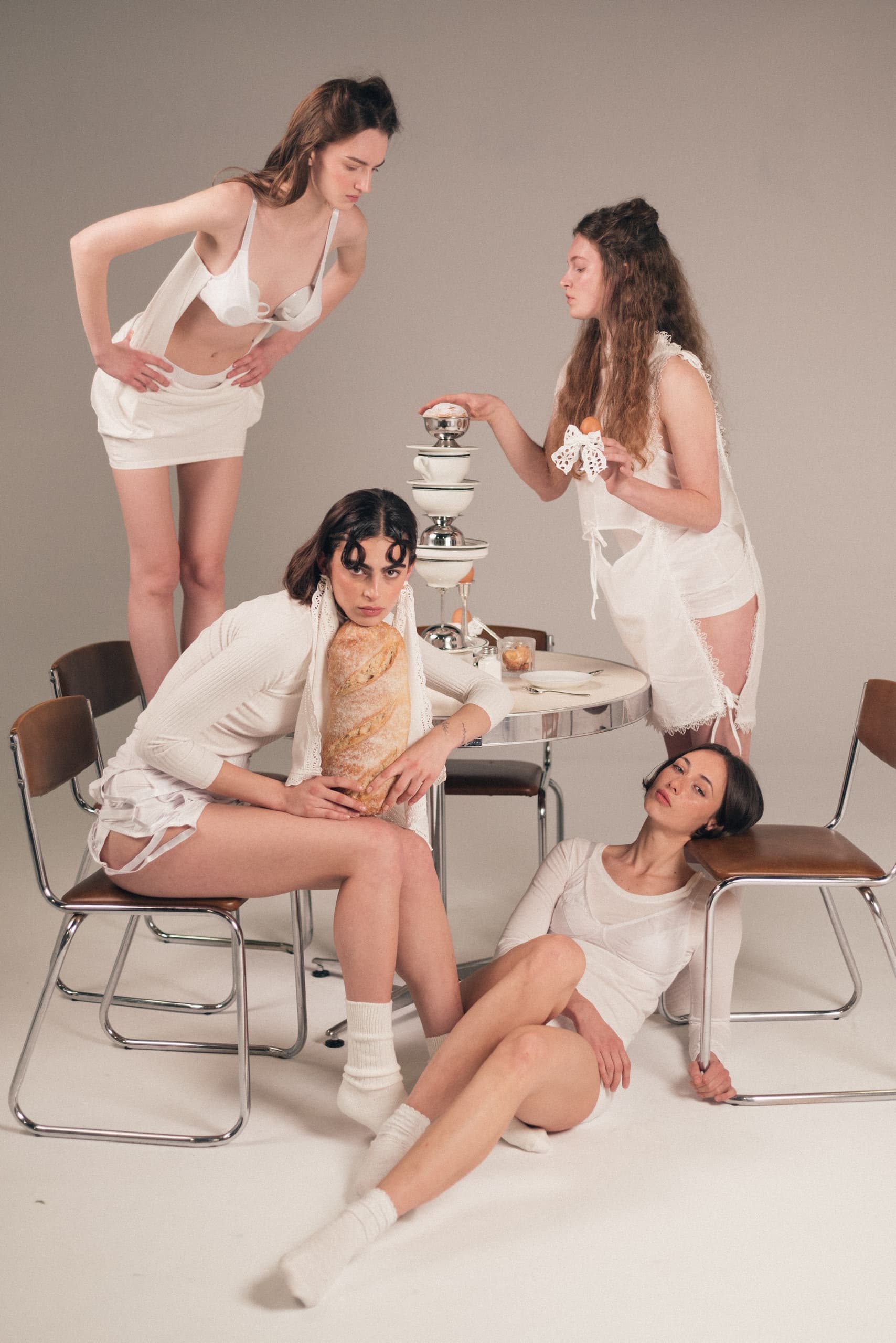 Fashionable women in white dine stylishly around a table display.