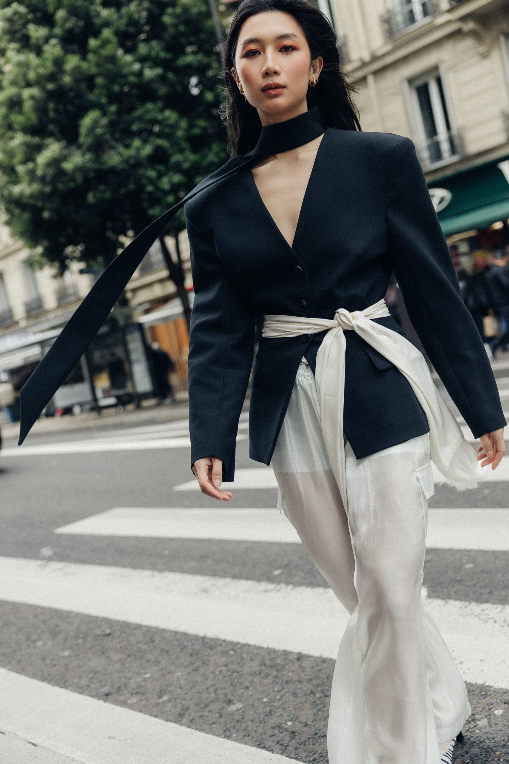 Fashionable woman in sleek outfit walking on city street, showcasing modern style.