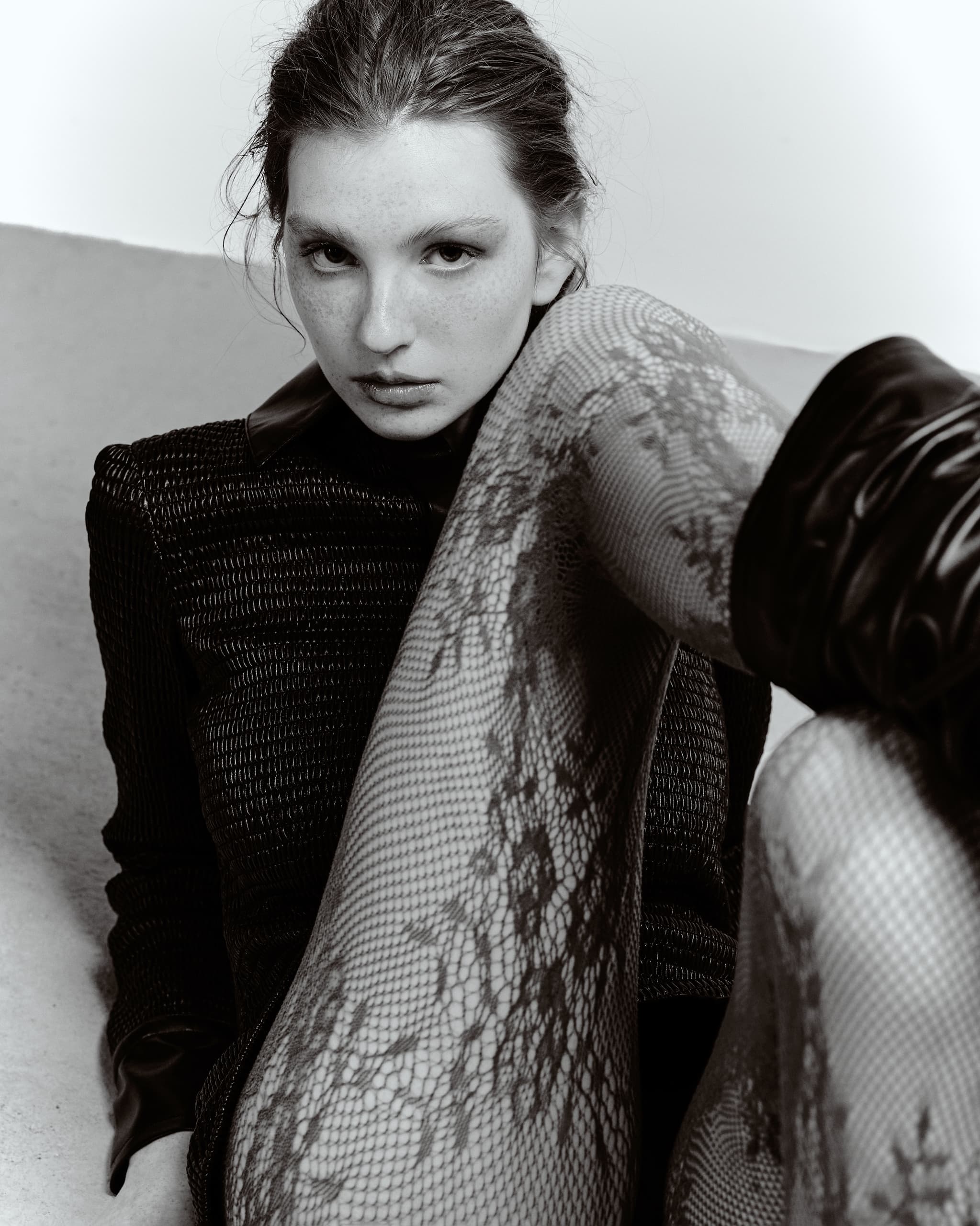 Fashion portrait of a woman in lace tights and textured clothing, black and white.