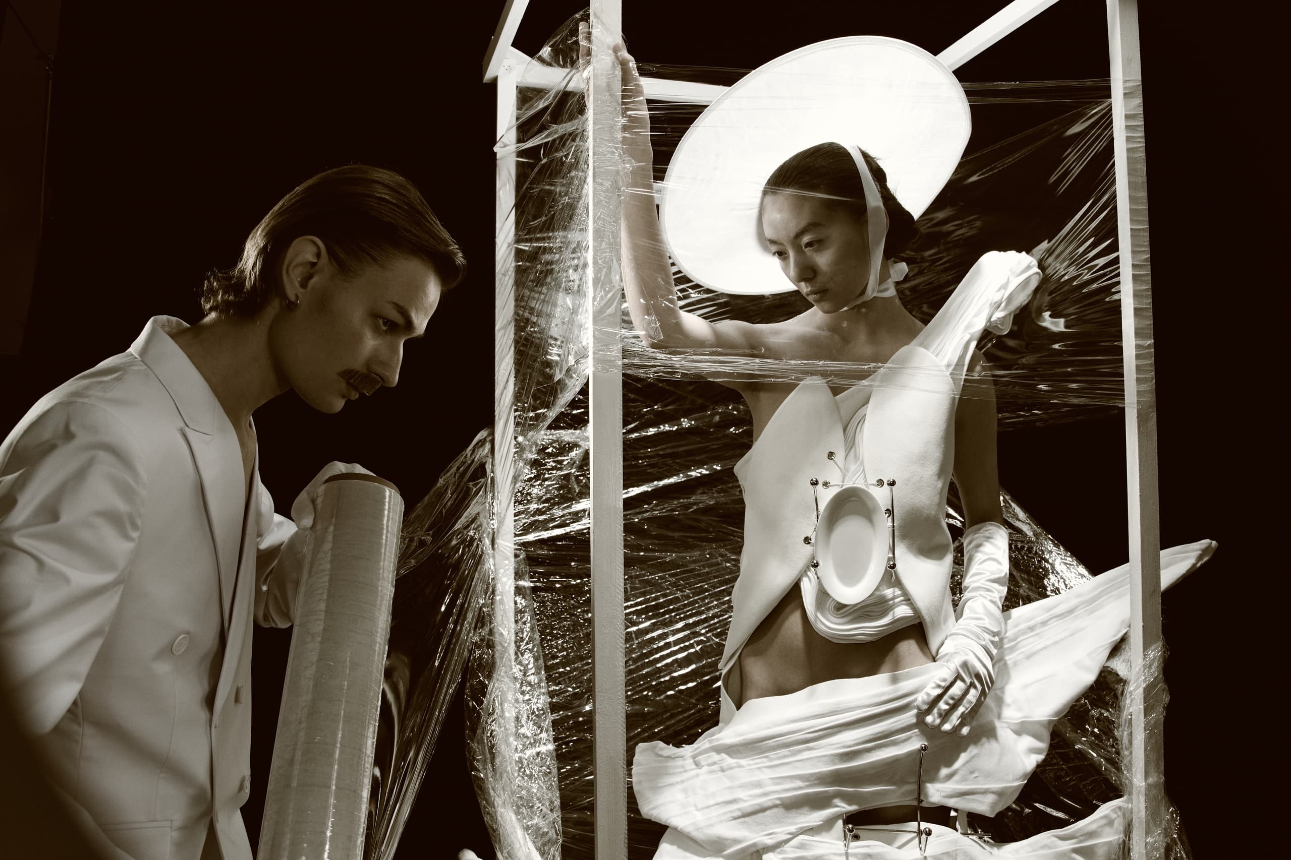 Futuristic fashion art scene with models in avant-garde outfits and wrapping film.