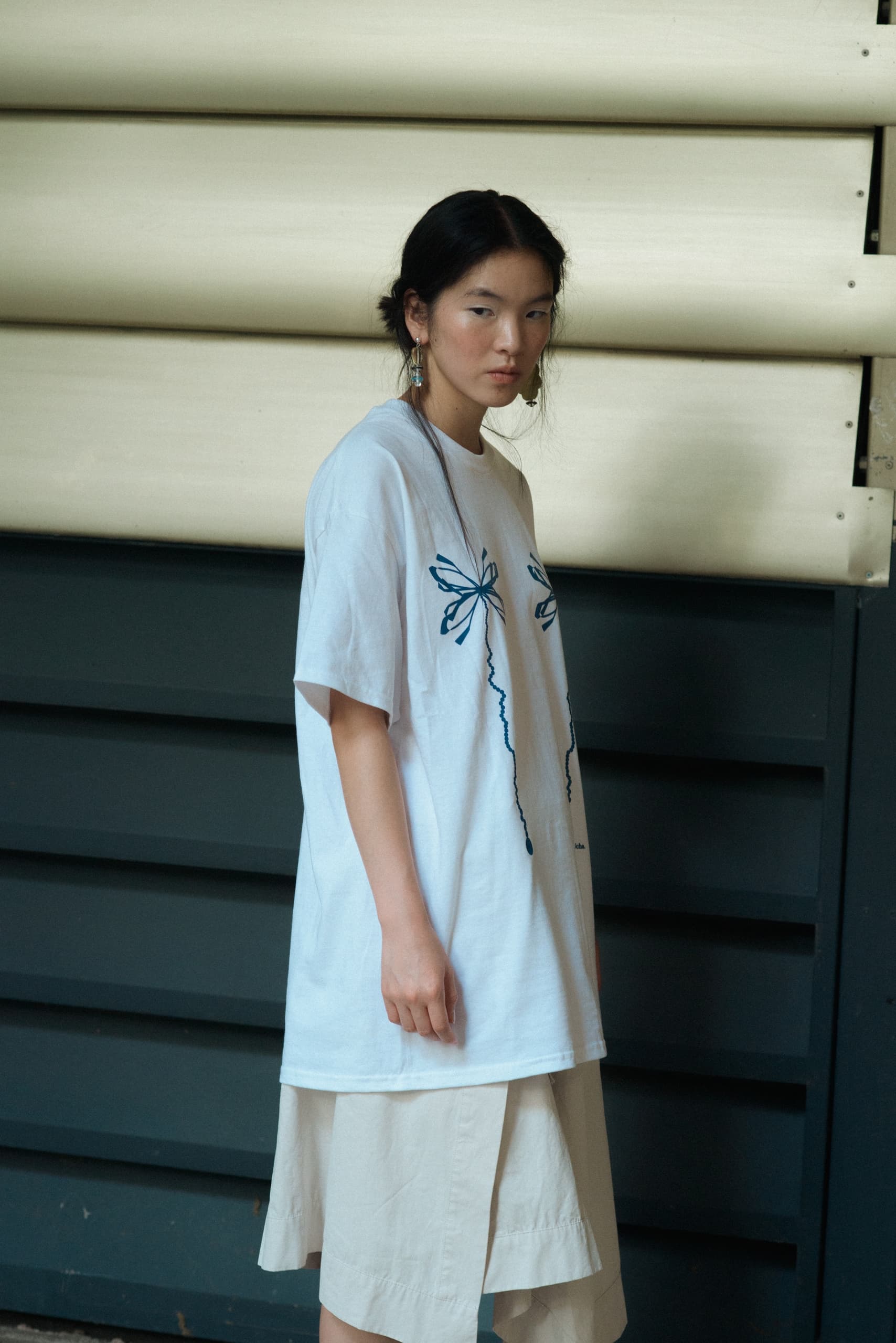 Woman in dragonfly printed shirt standing indoors against beige and navy backdrop.