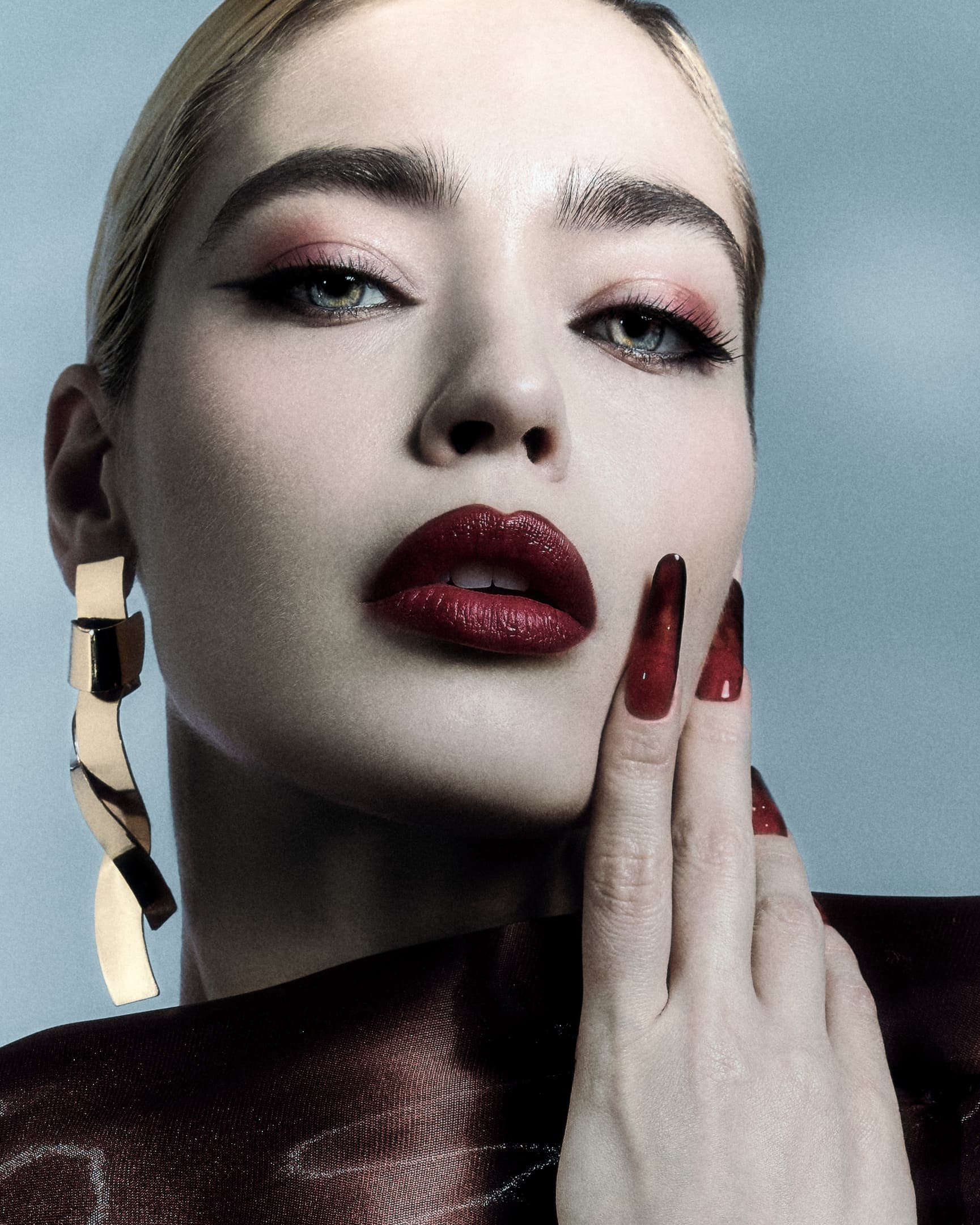 Fashion portrait with bold red lips and statement gold earrings.