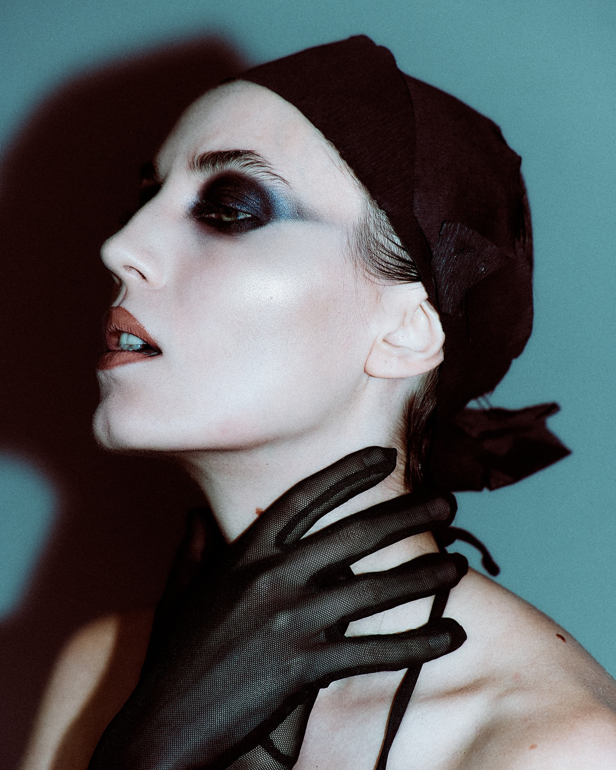 Avant-garde portrait with dramatic makeup and black glove accessory.