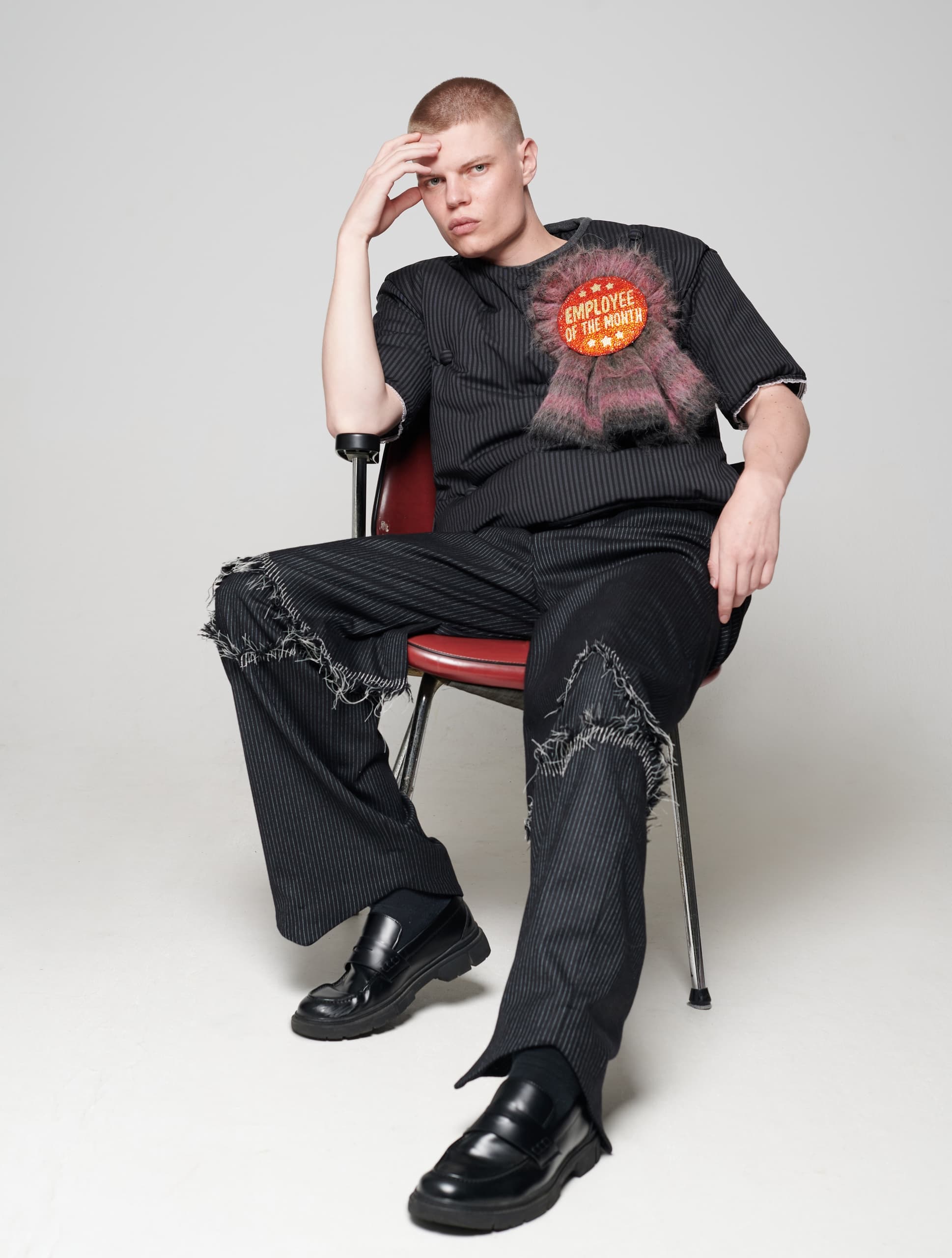 Man seated in rugged attire with Employee of the Month badge.