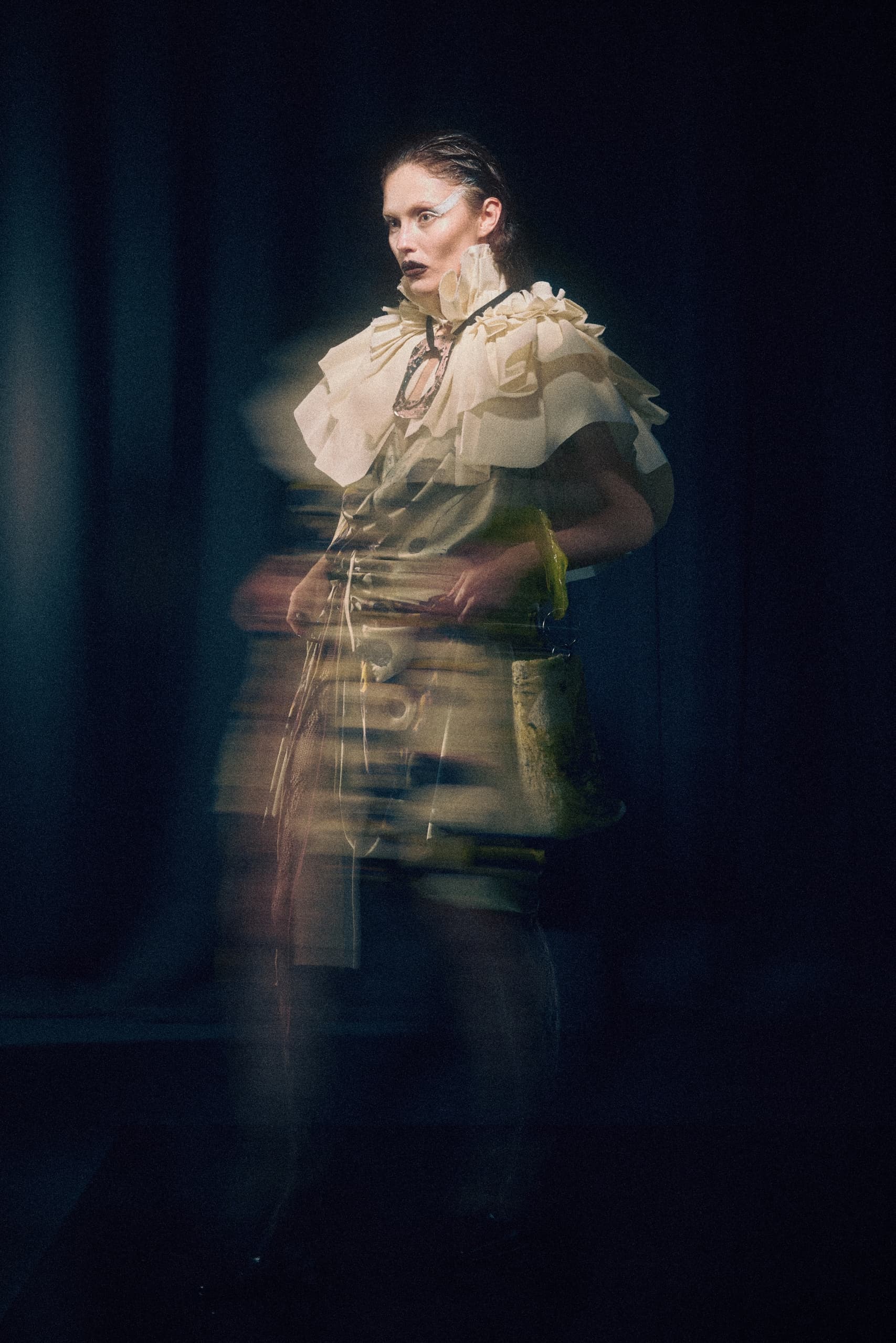 Ethereal fashion model in layered ruffled dress, blurred motion effect.