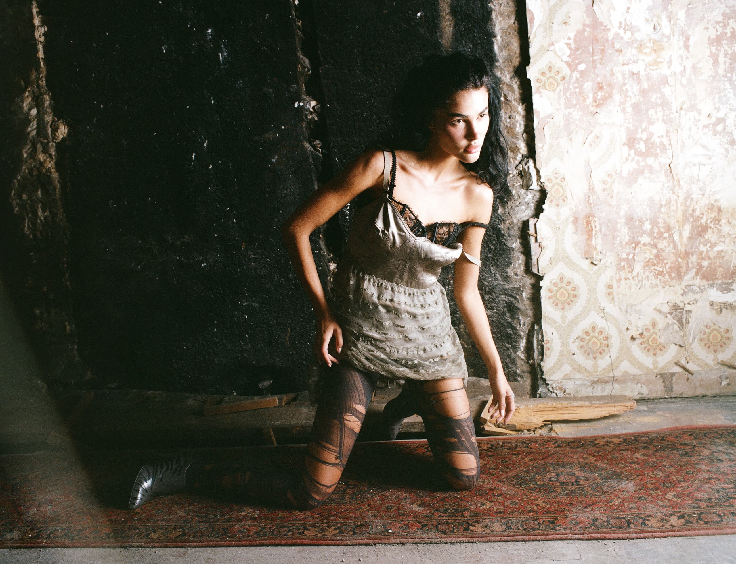 Woman in stylish outfit poses against vintage textured wall.