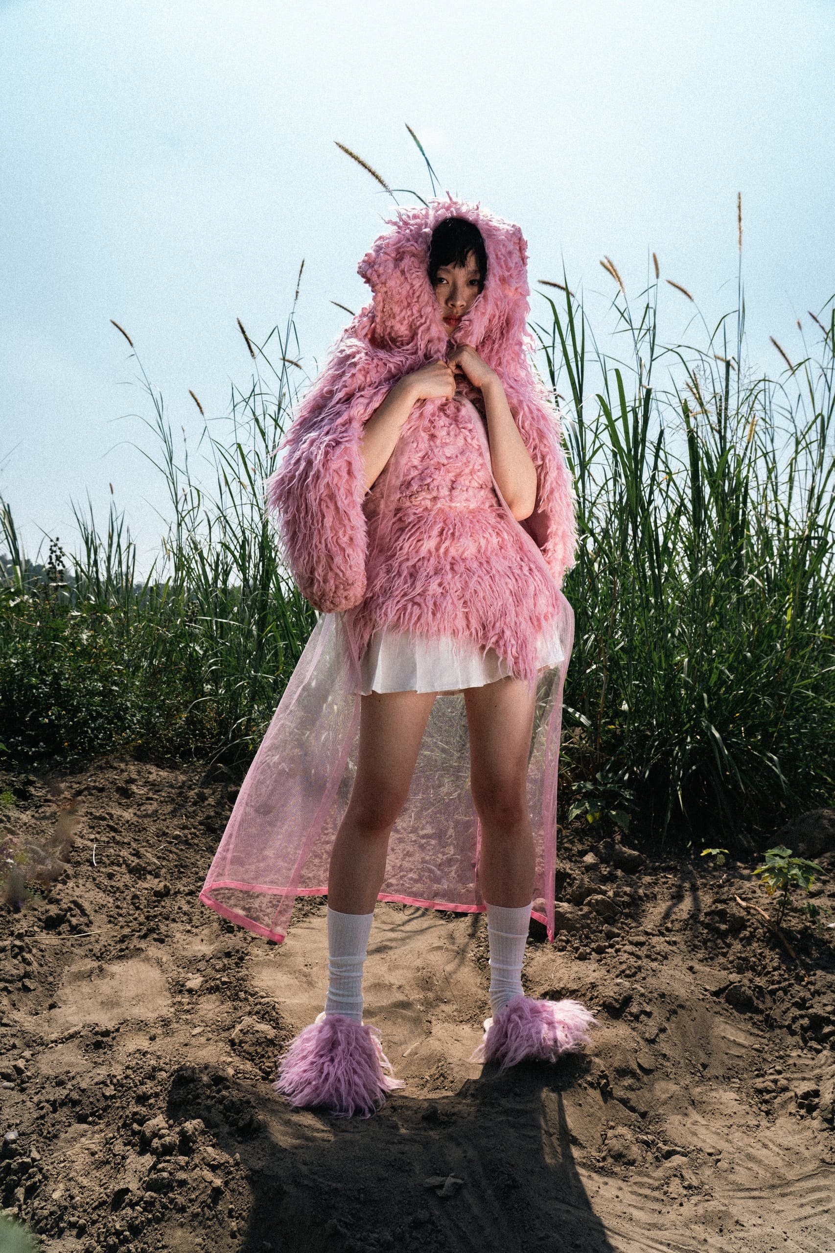 Person in a pink fluffy outfit standing outdoors, creative fashion scene.