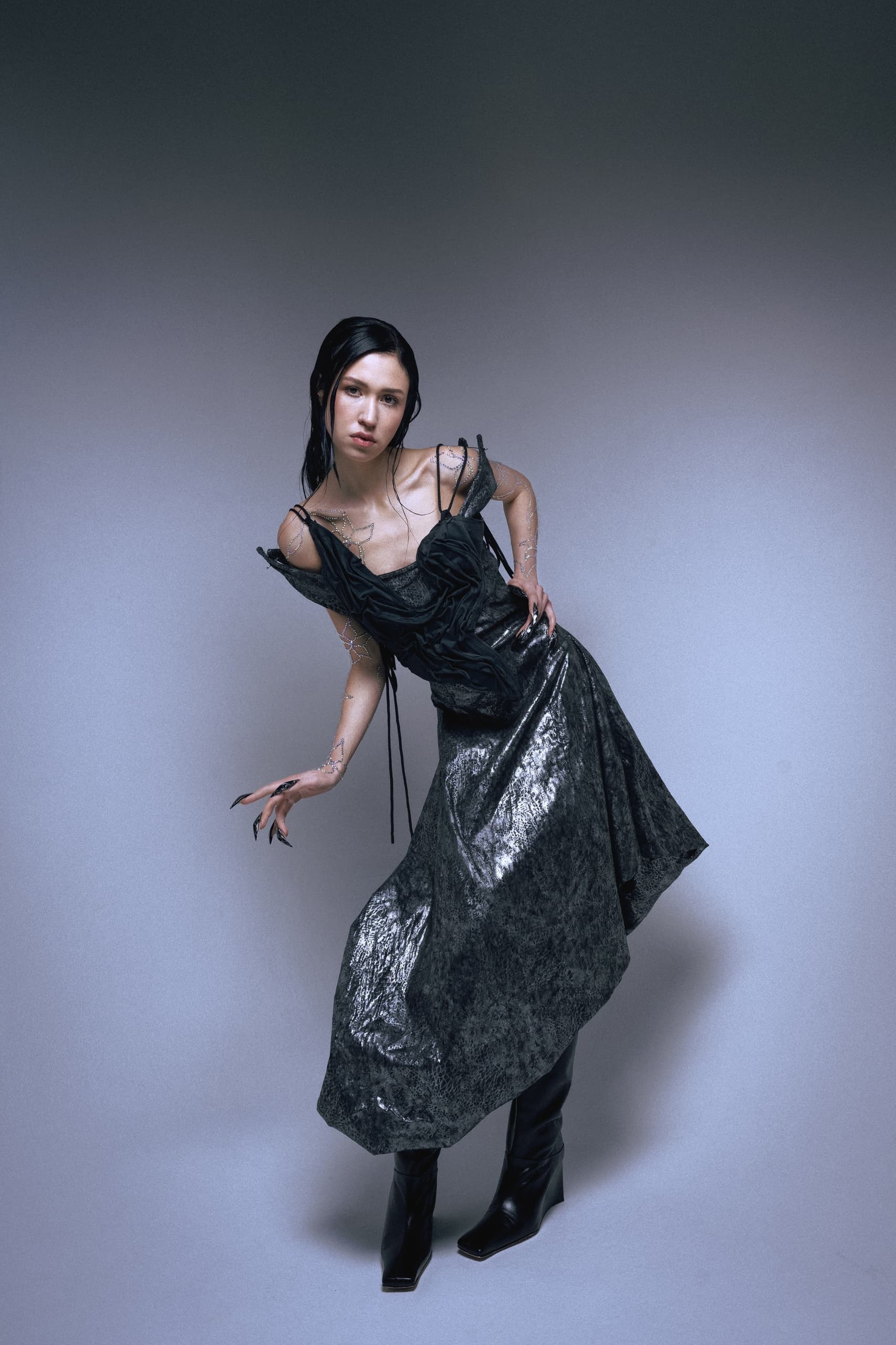 Fashion model in gothic black dress posing on gray background.