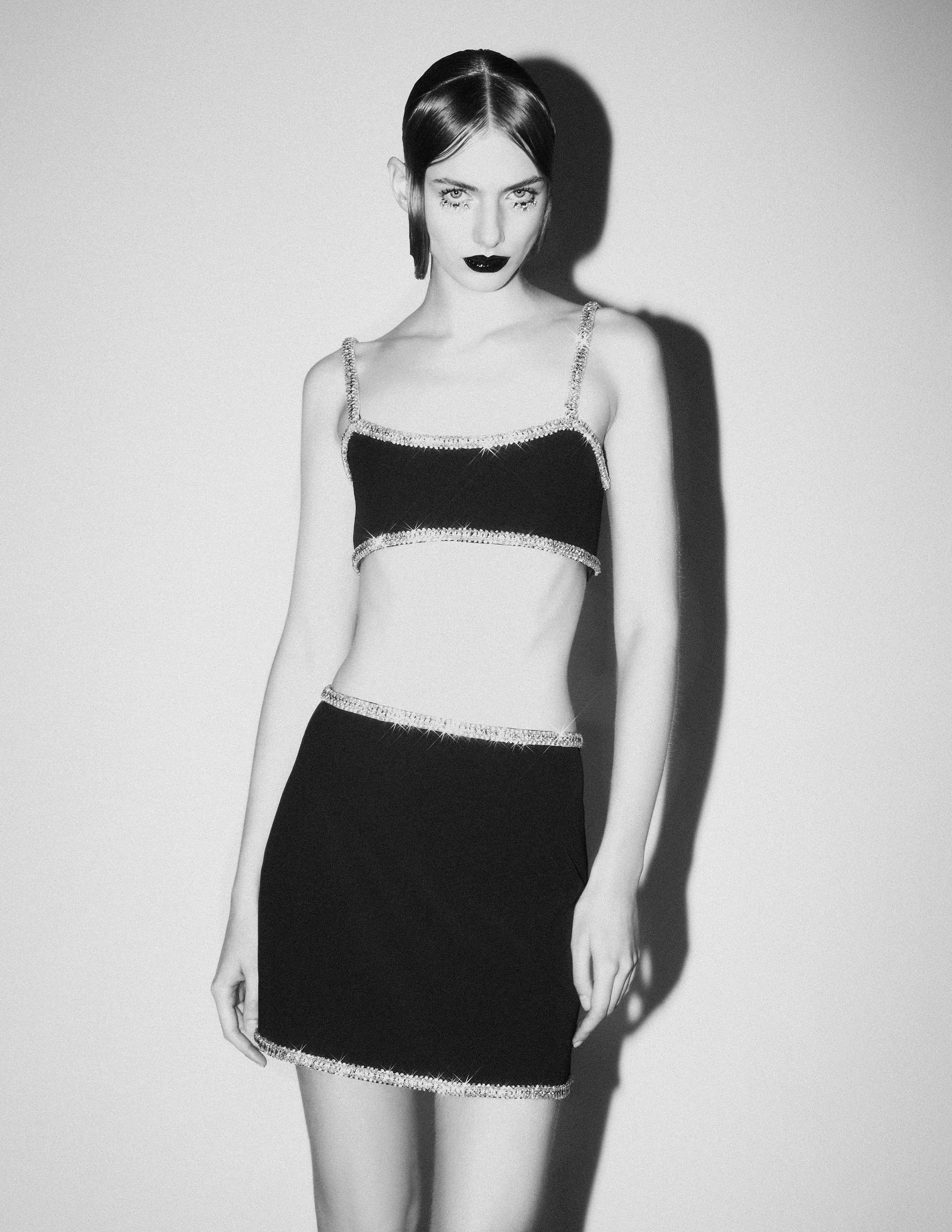 Black and white photo of a model in a stylish two-piece outfit.
