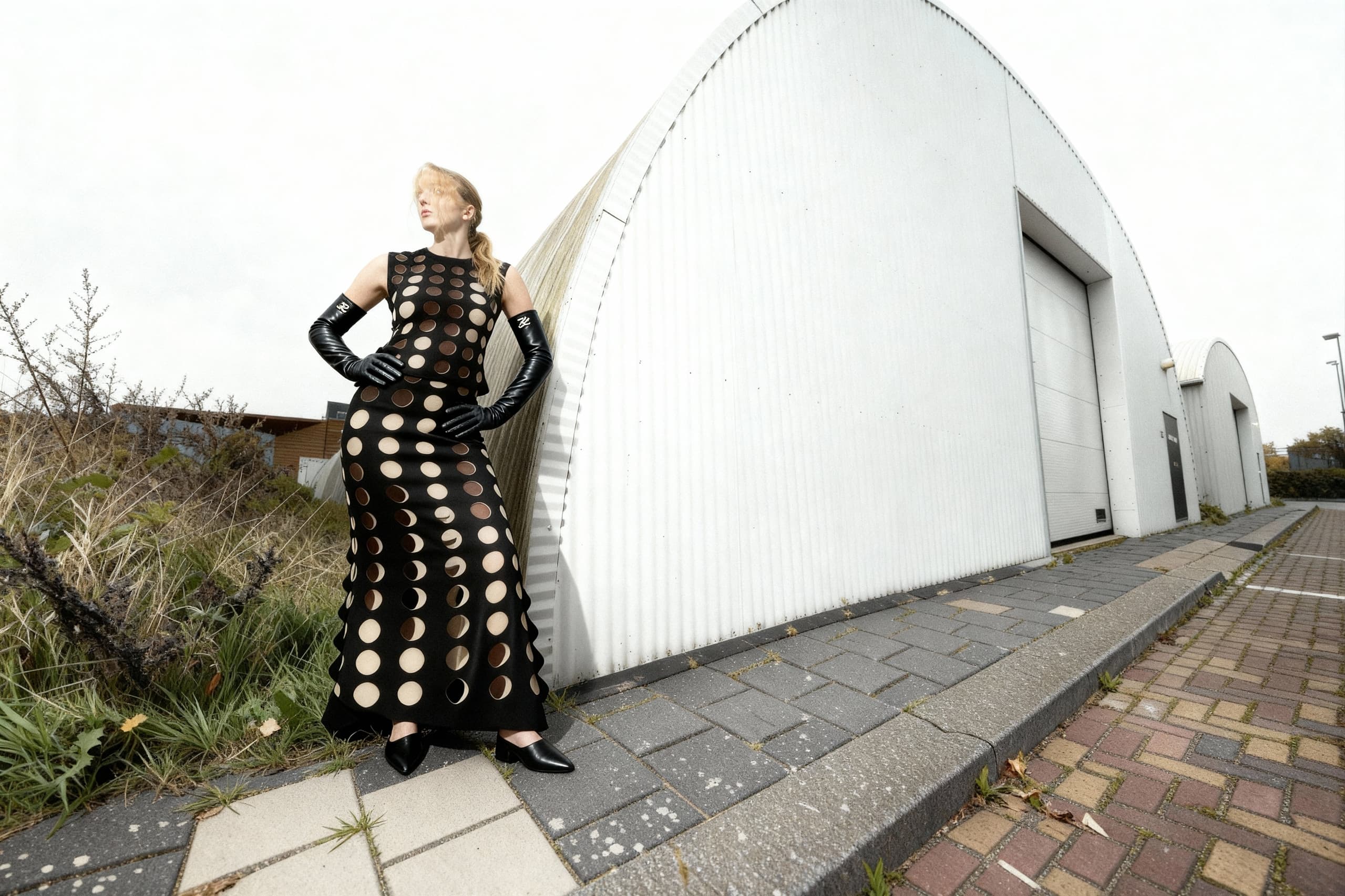 Modern fashion: Woman in polka dot dress, black gloves, urban background.