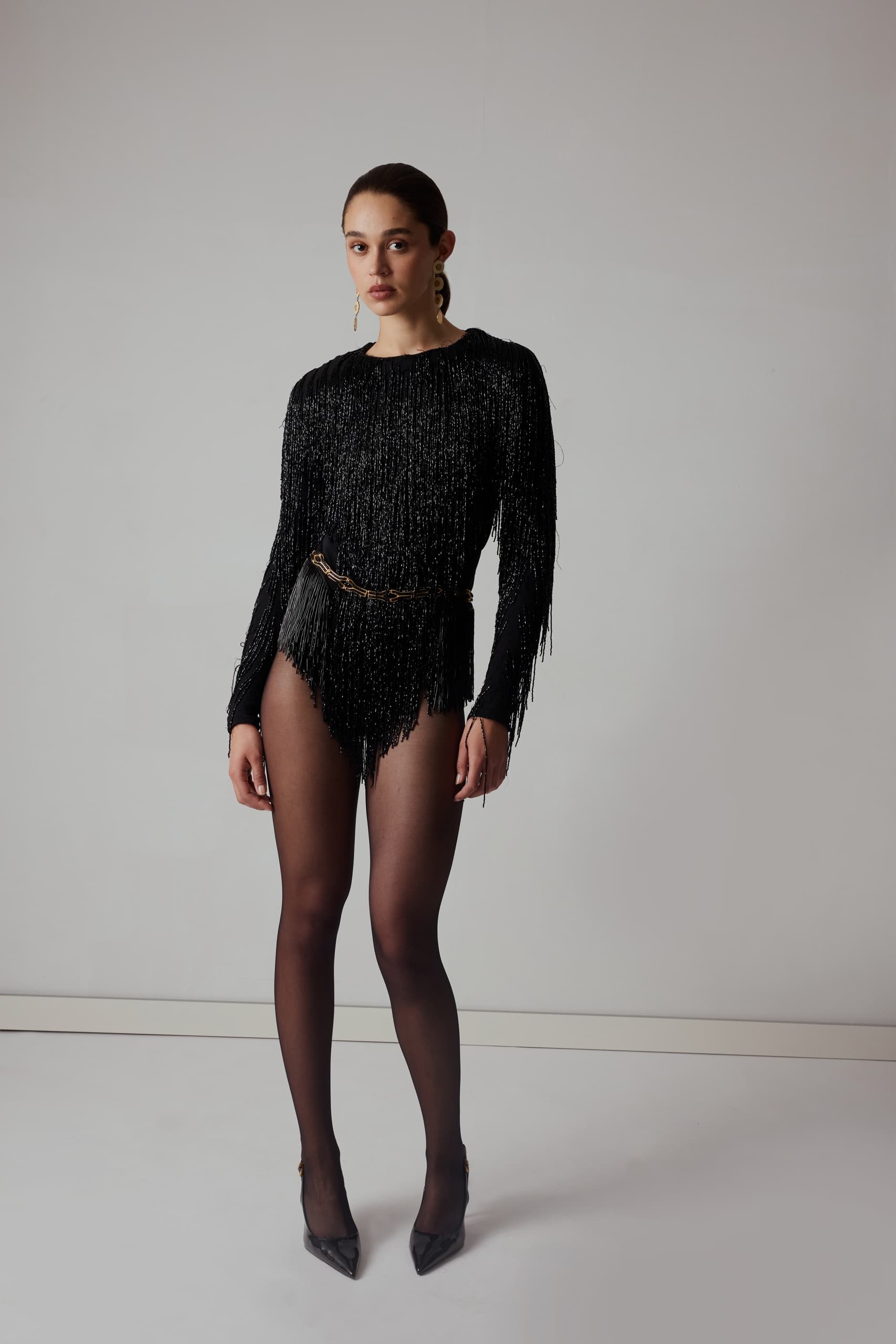 Woman in elegant black fringe outfit with tights and heels.