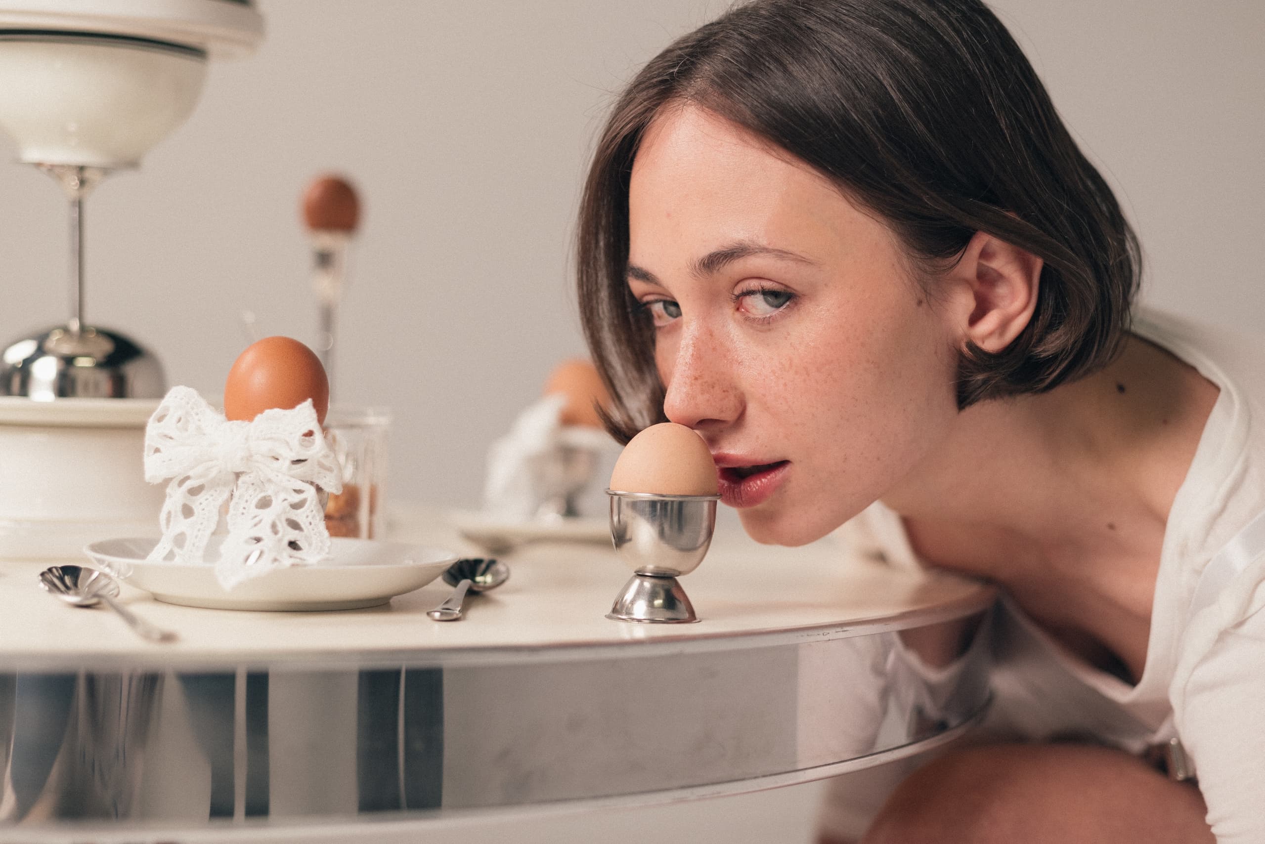 Woman close to egg in cup on elegant table setting.