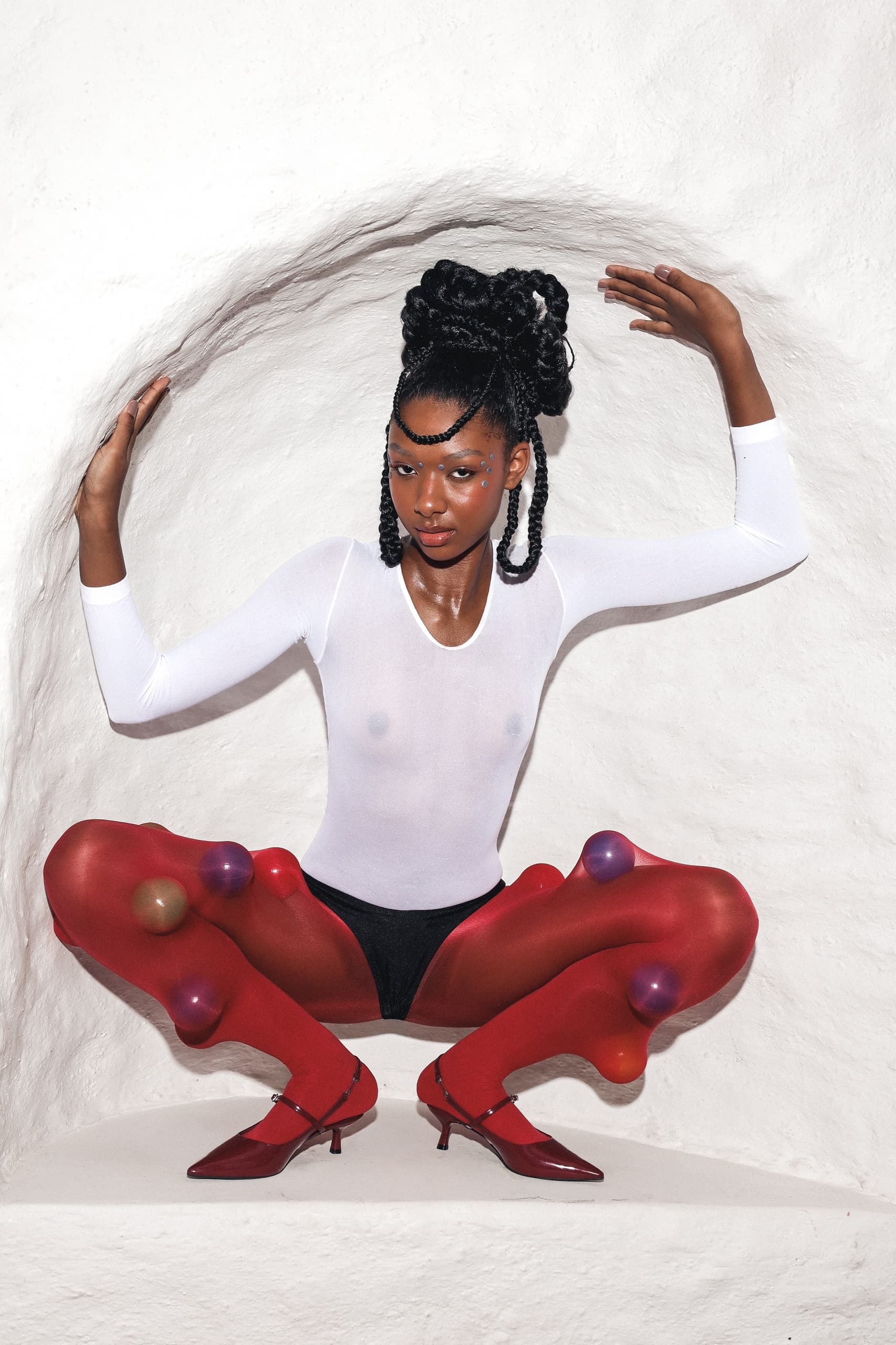 Stylish woman in red tights and white top seated in an artistic pose.