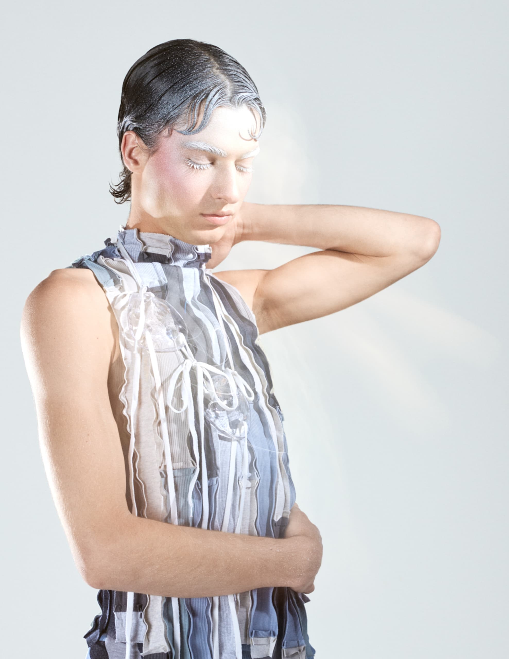 Person with artistic makeup in a striped outfit, striking a serene pose.