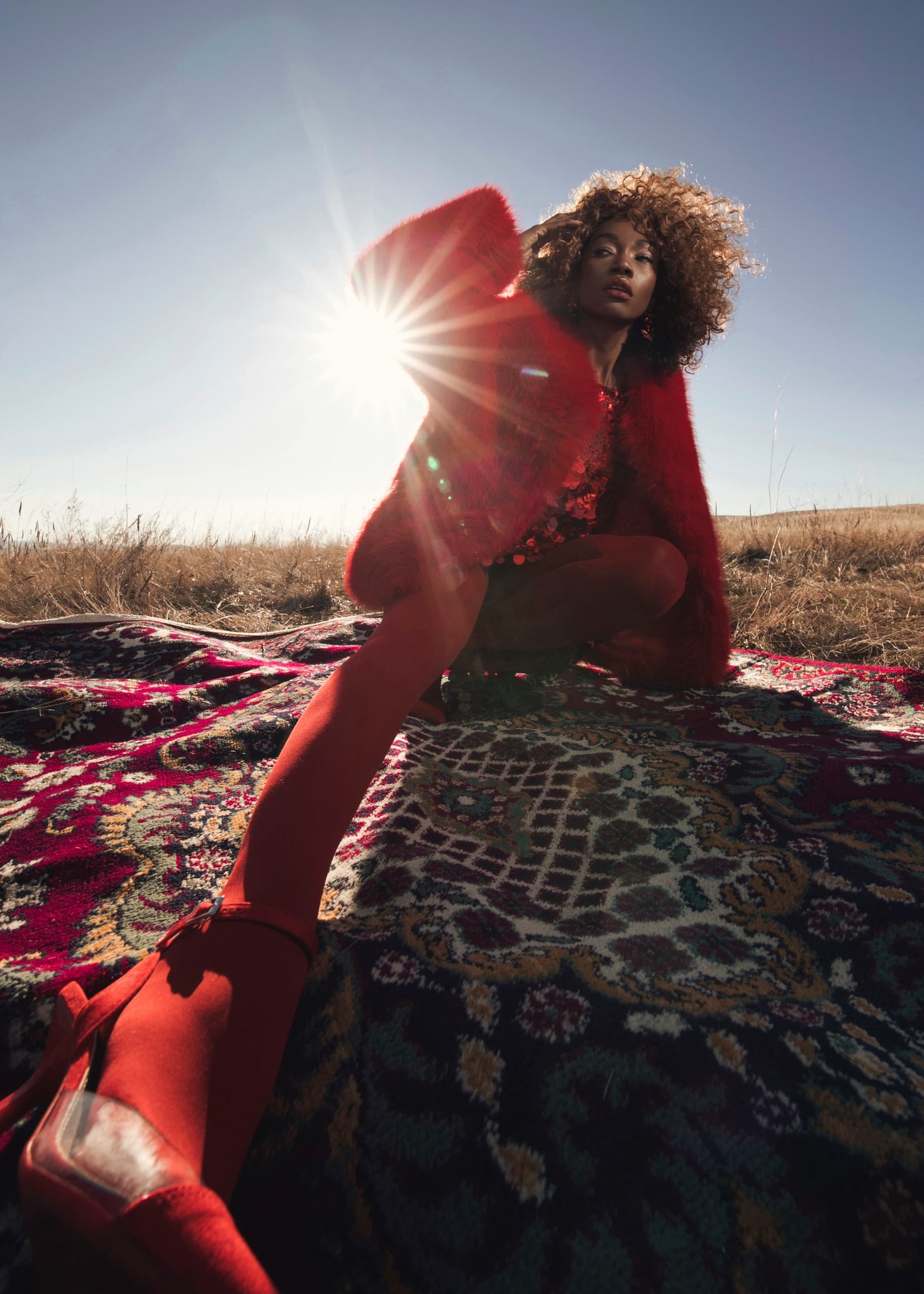 Fashionable woman in red, sunlight flare, outdoor photo on colorful rug.