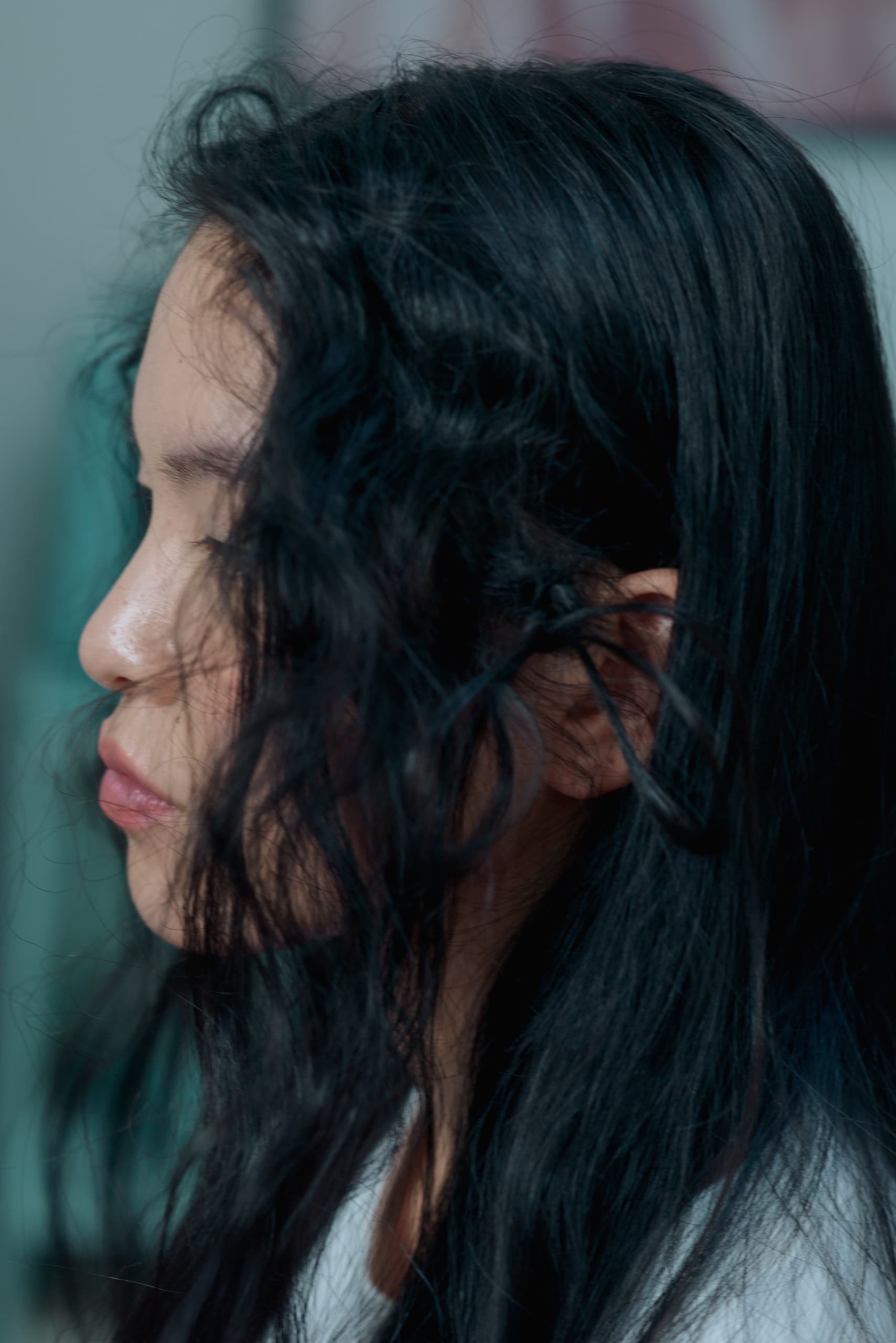 Woman with long, wavy black hair in profile, eyes closed.