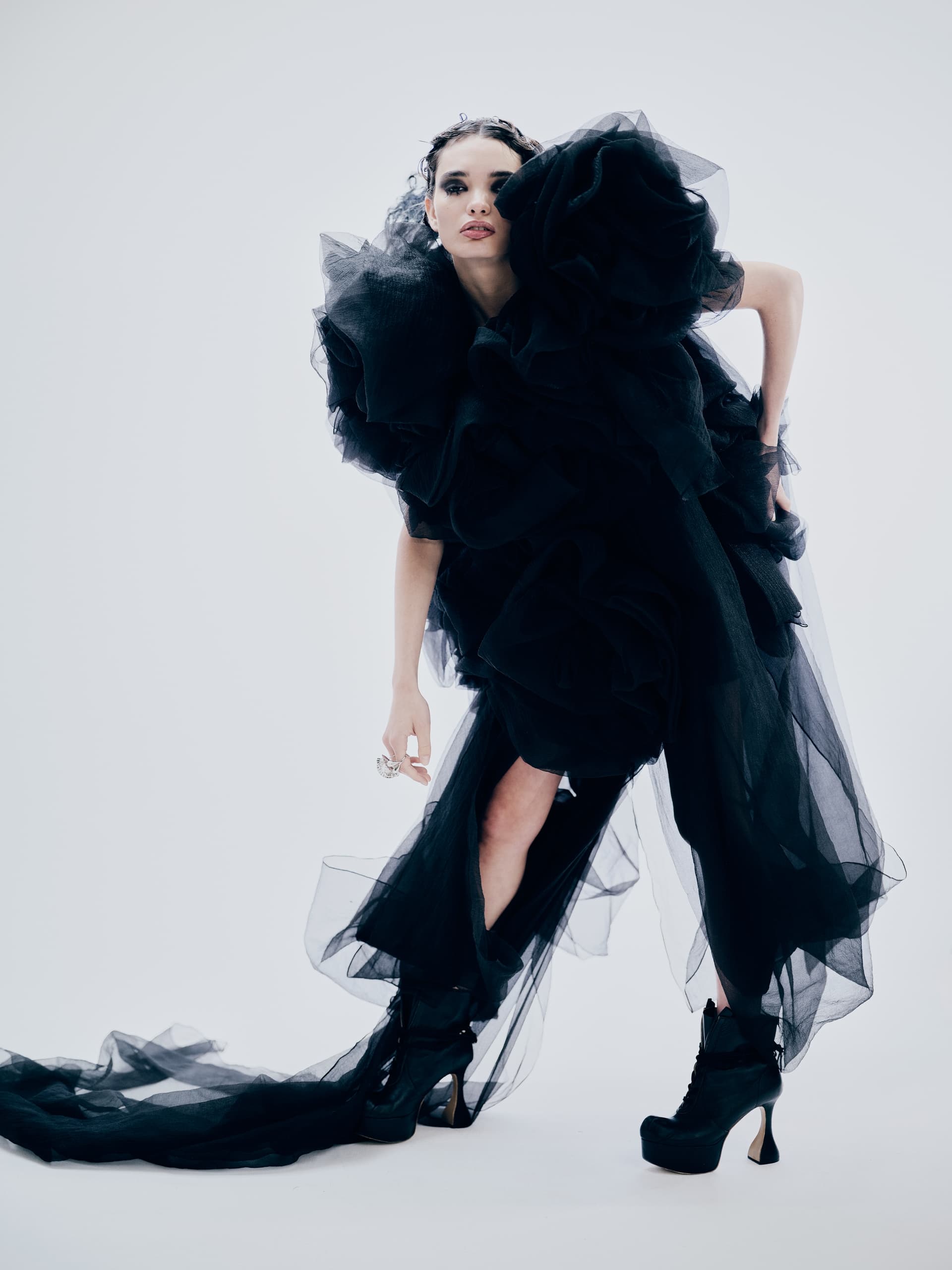 Model in an avant-garde black gown with dramatic ruffles and platform boots.
