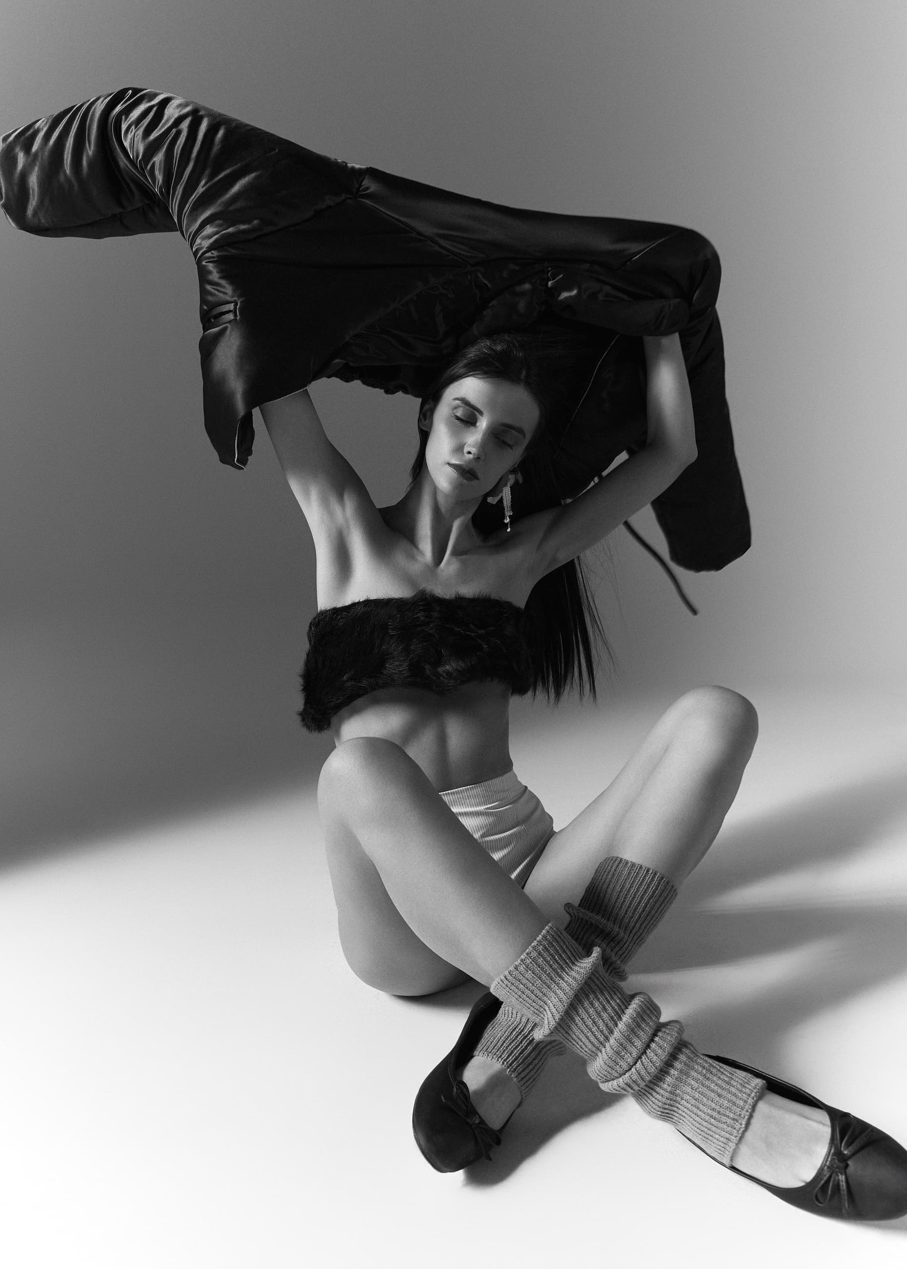 Woman in fashion pose with jacket in monochrome studio setting.