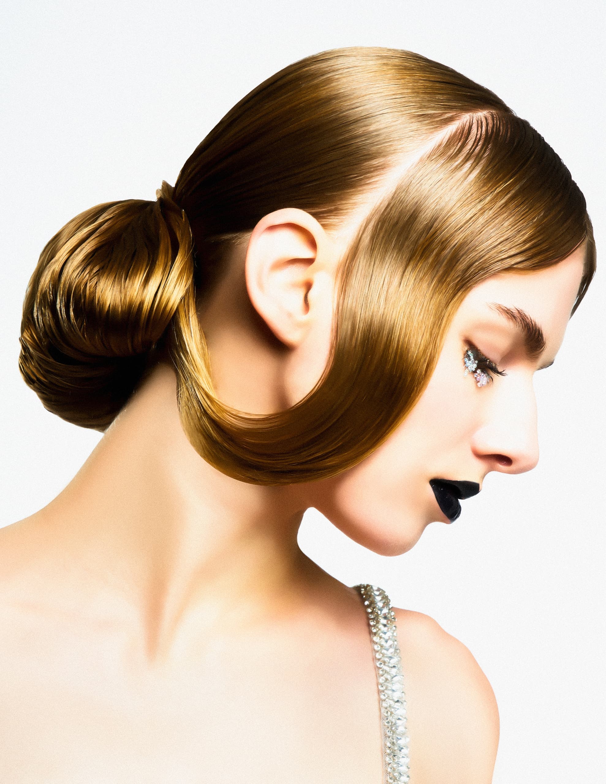 Sleek hairstyle with side-swept bun and black lipstick on fashion model.