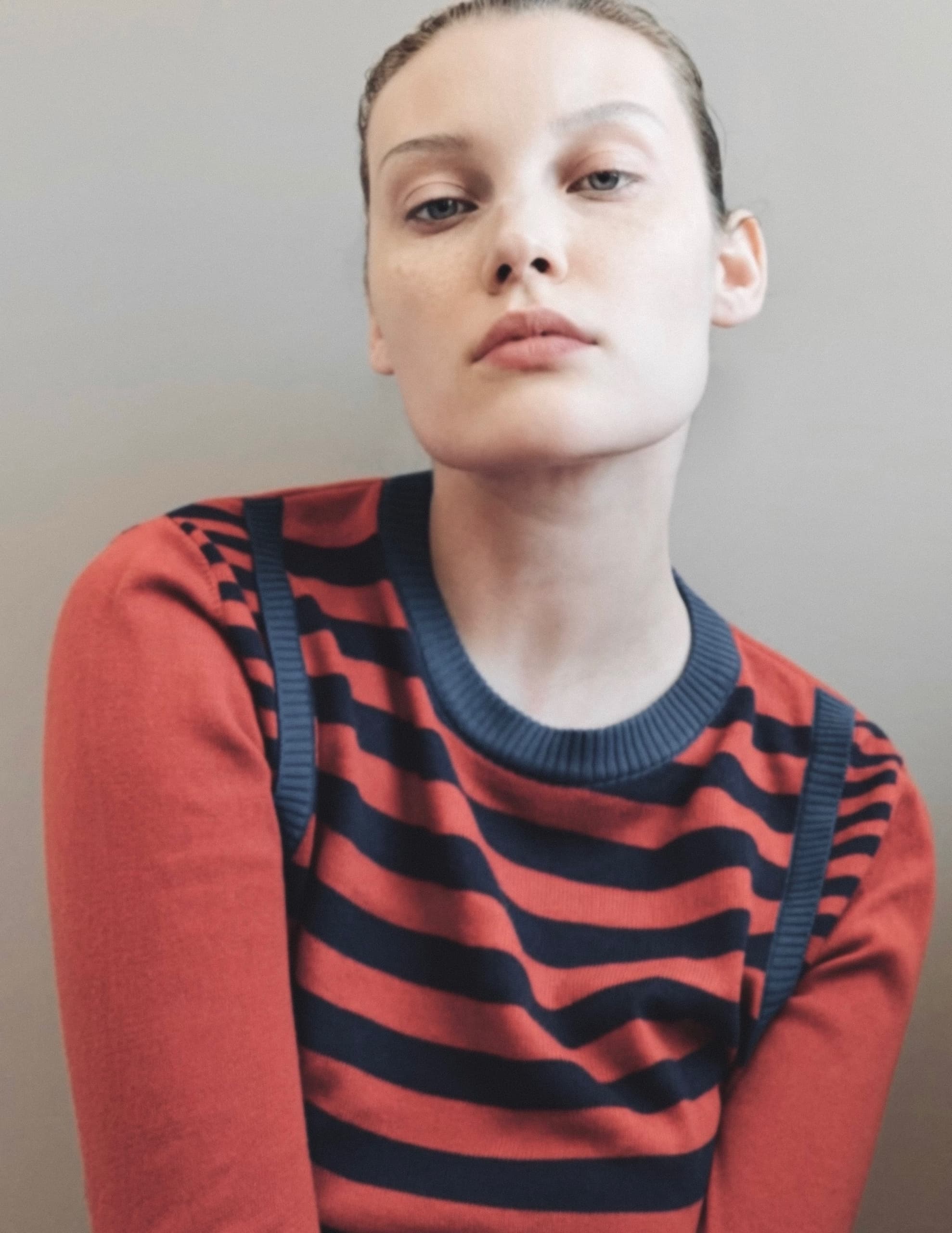 Woman in a red and black striped sweater, gazing confidently.