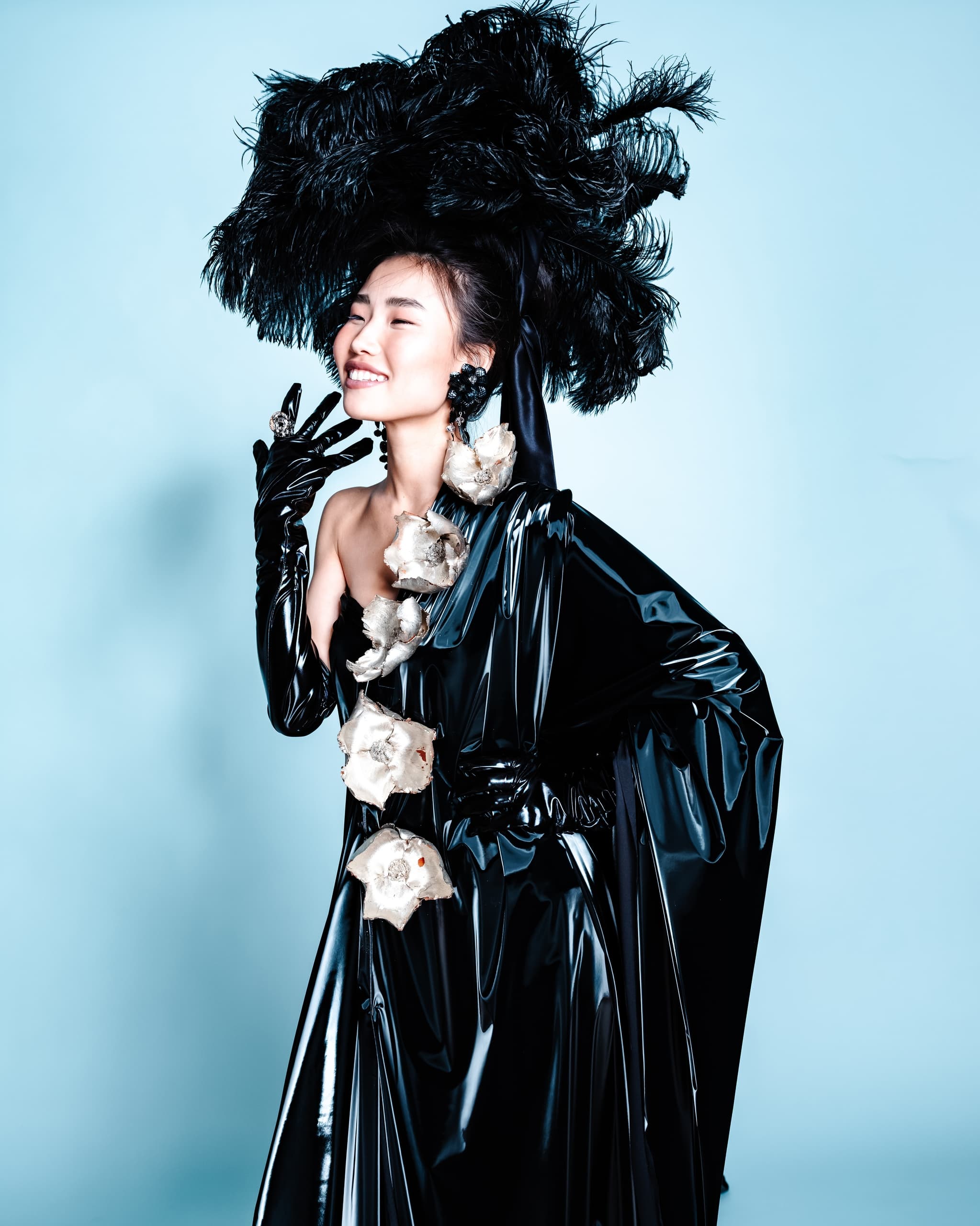 Fashion model in avant-garde black outfit with elaborate feathered headpiece.