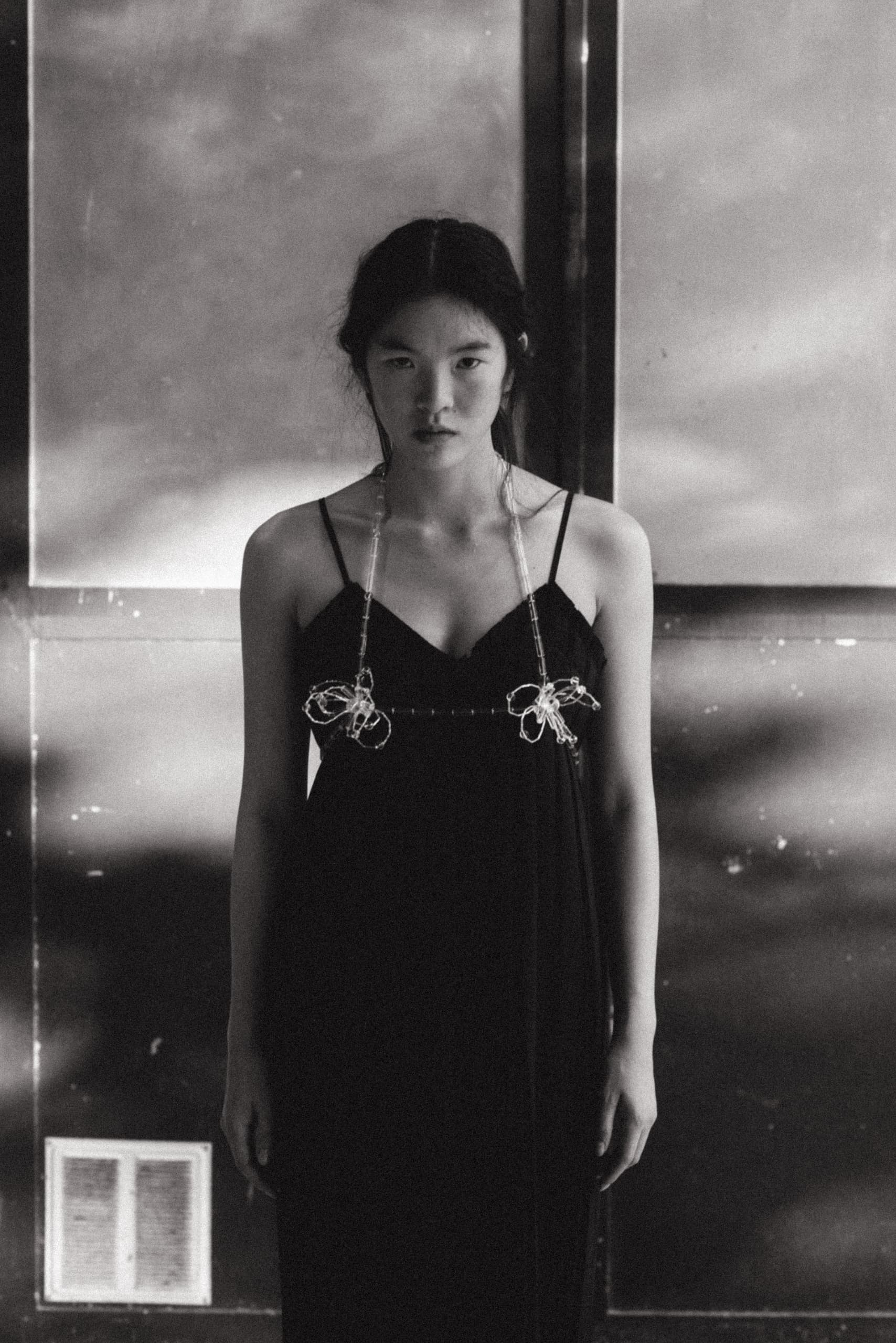 Black and white portrait of a woman in a dark dress, standing dramatically.