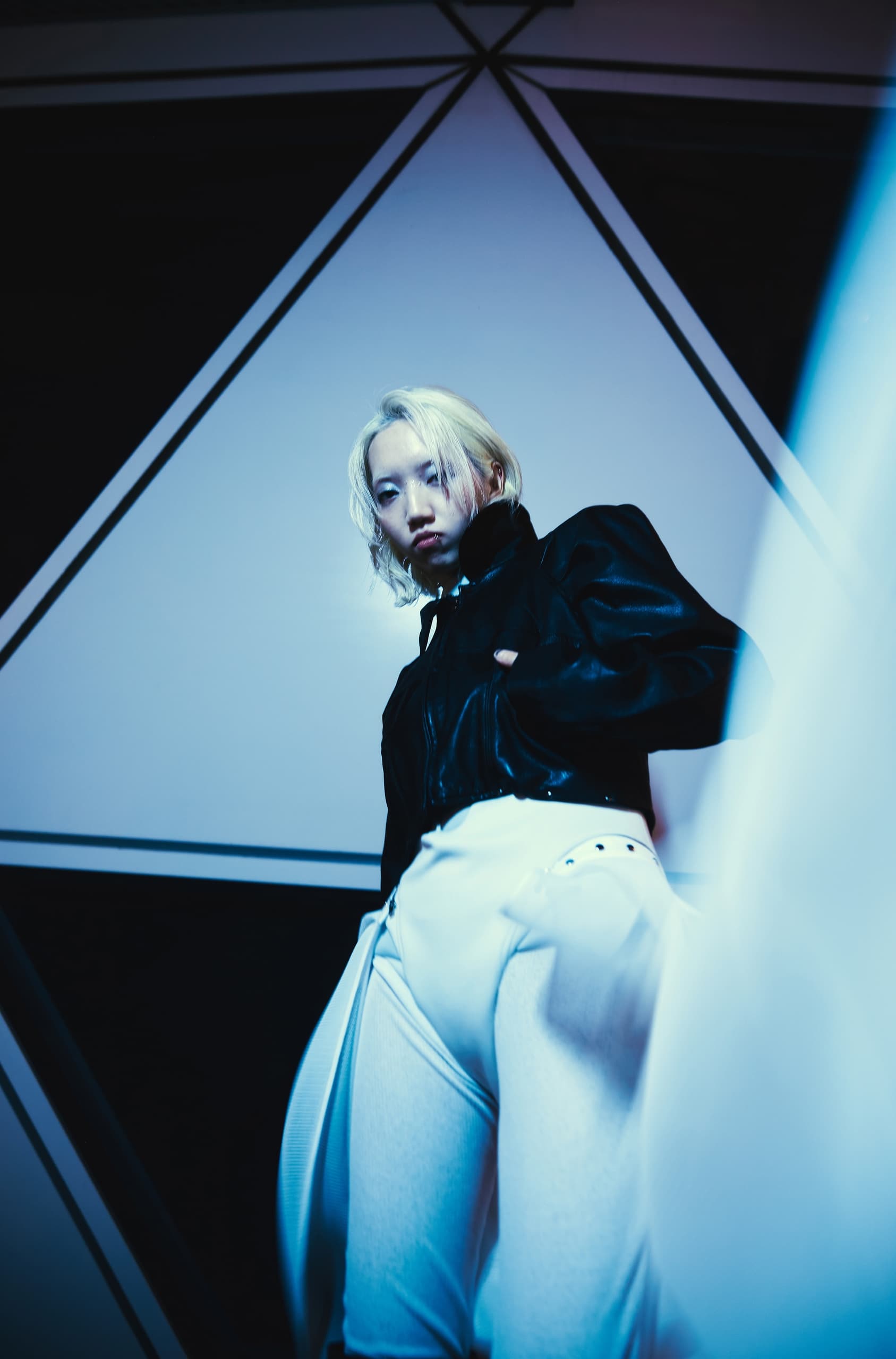 Fashion model in edgy black and white clothing against a geometric backdrop.