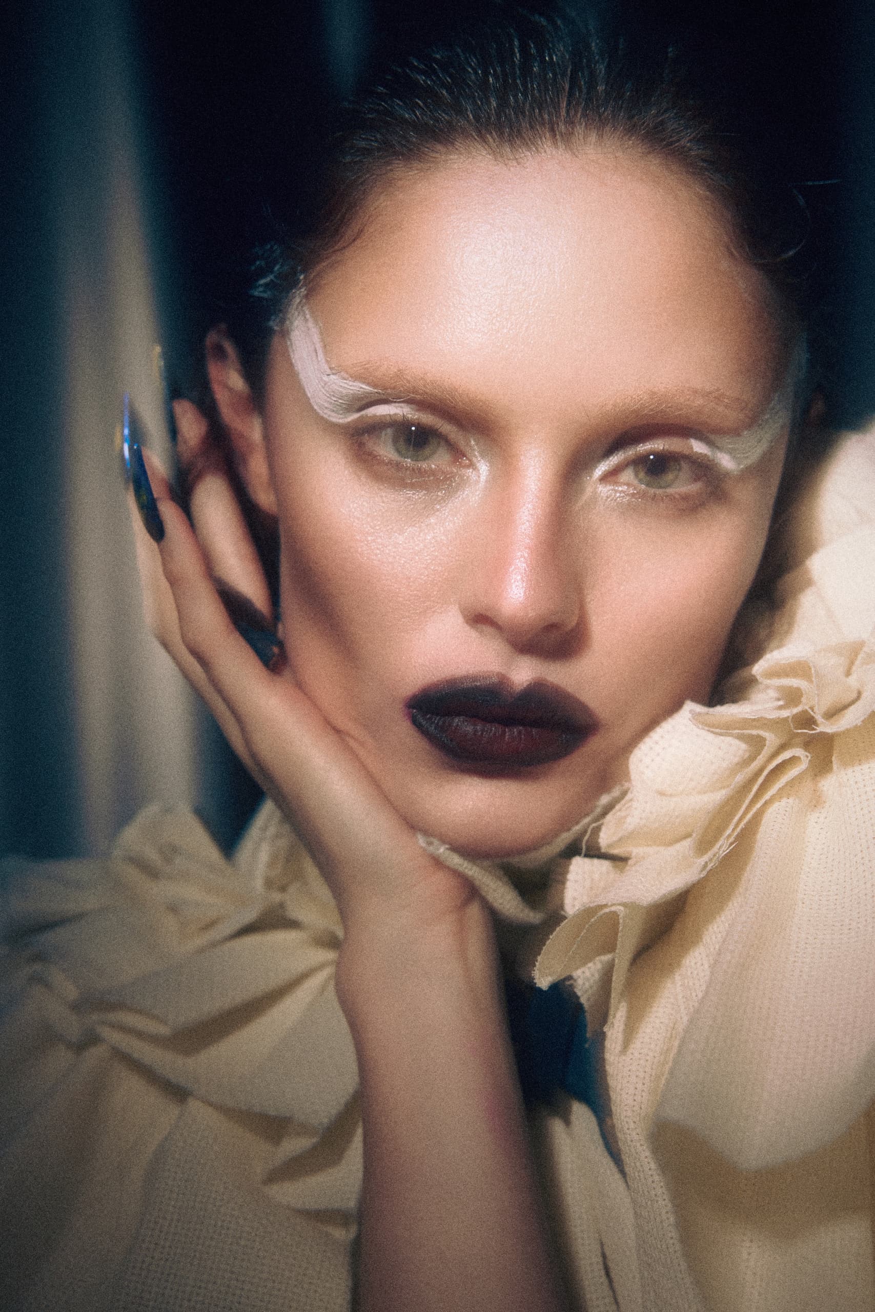 Fashion model with dramatic makeup and stylish outfit in close-up portrait.