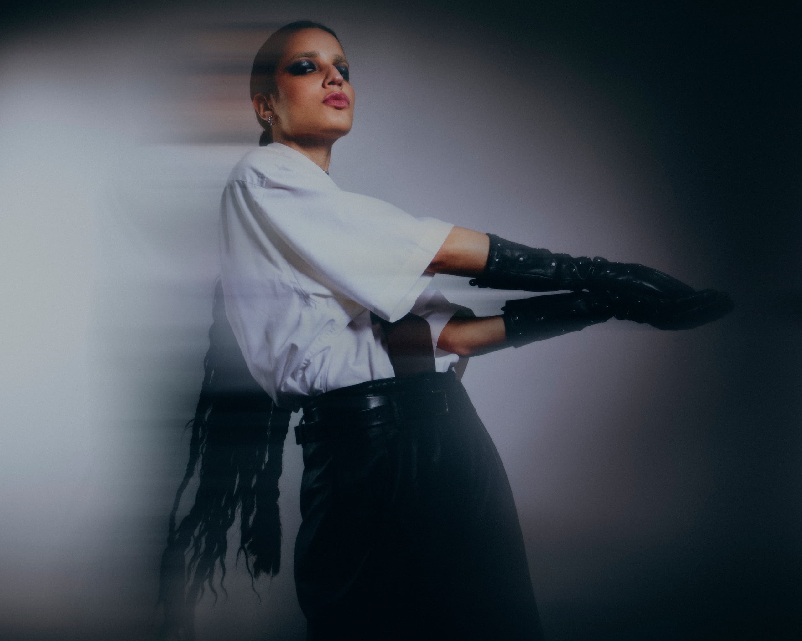 Fashion model in black gloves, white top, blurred artistic effect.