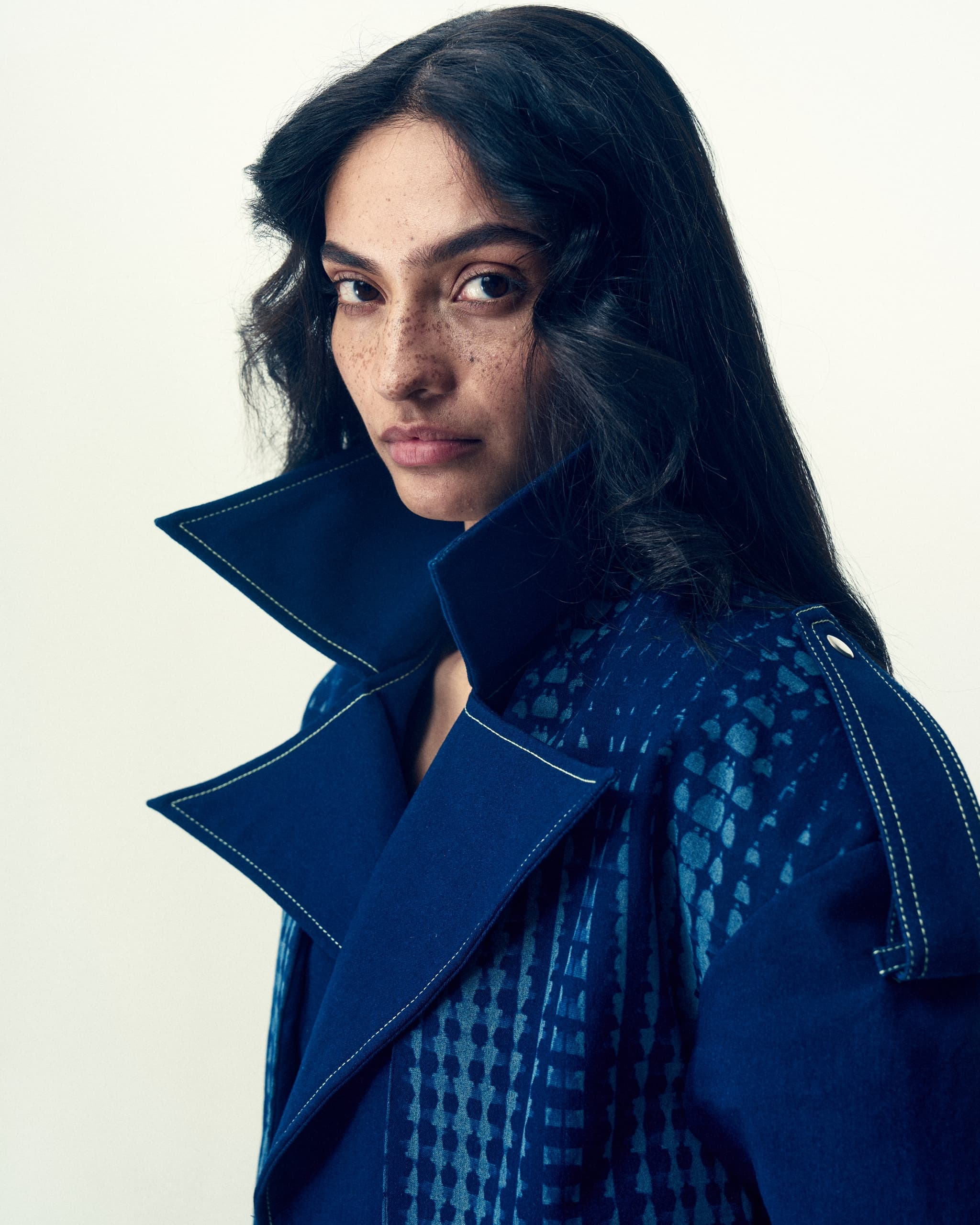 Model in stylish blue coat with intricate patterns.