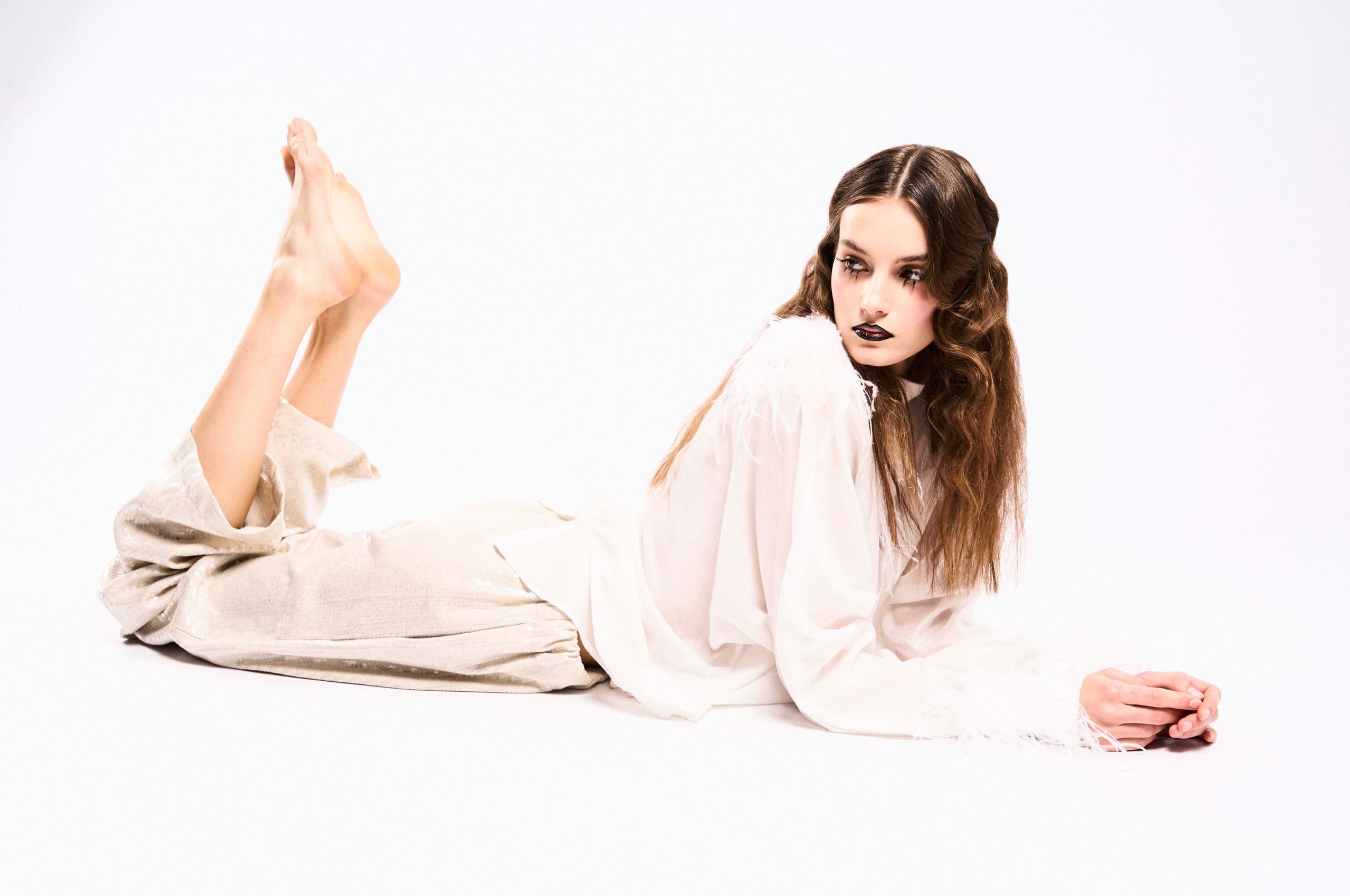 Model posing elegantly in white outfit on a minimalist background.