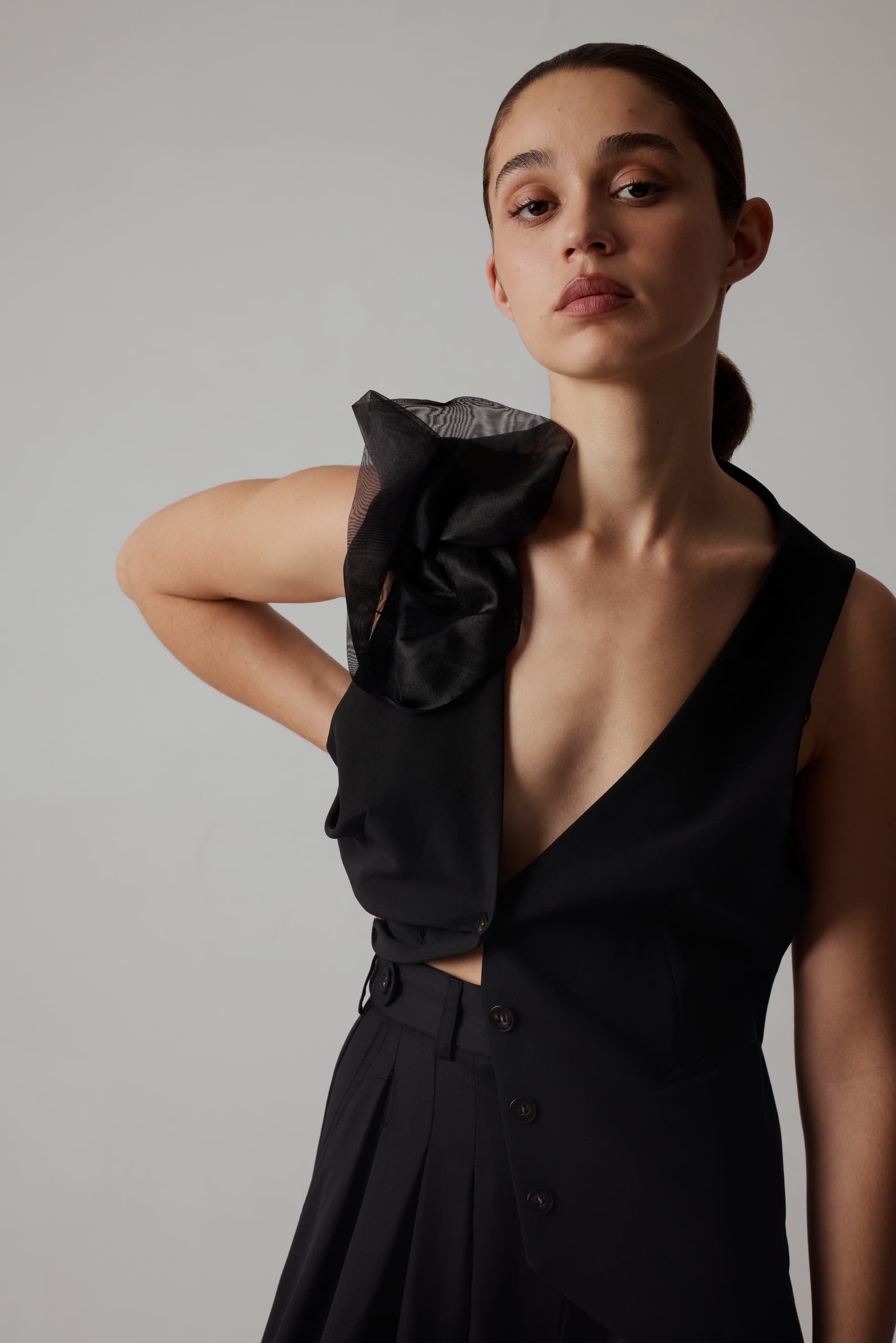 Fashion model in stylish black outfit and sheer shoulder accessory.