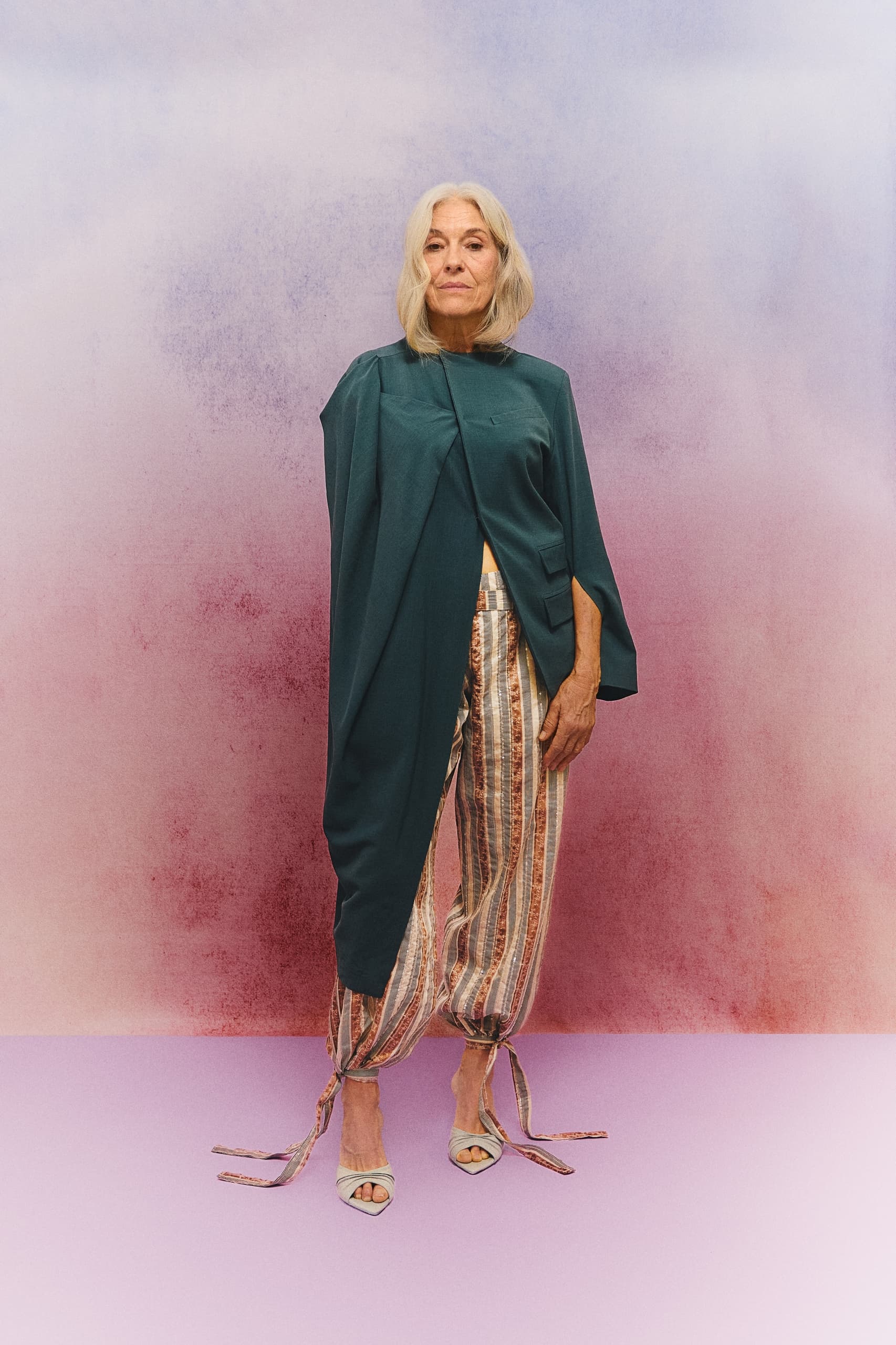 Stylish woman in colorful, modern outfit against vibrant background.