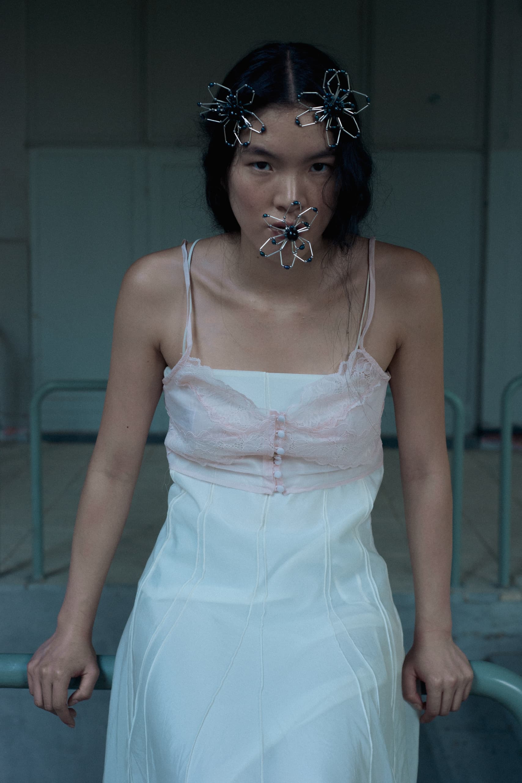 Woman in white dress with artistic metal accessories on face and hair.