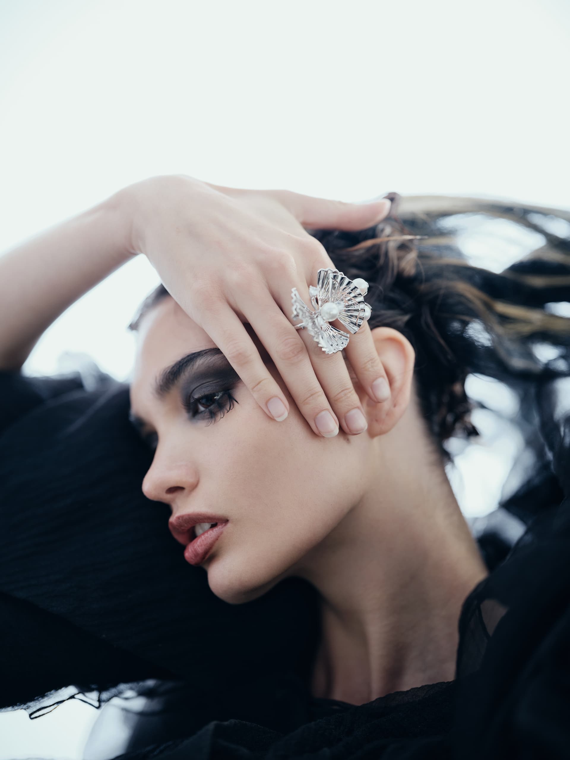 Woman with striking makeup and ornate silver ring striking a dramatic pose.
