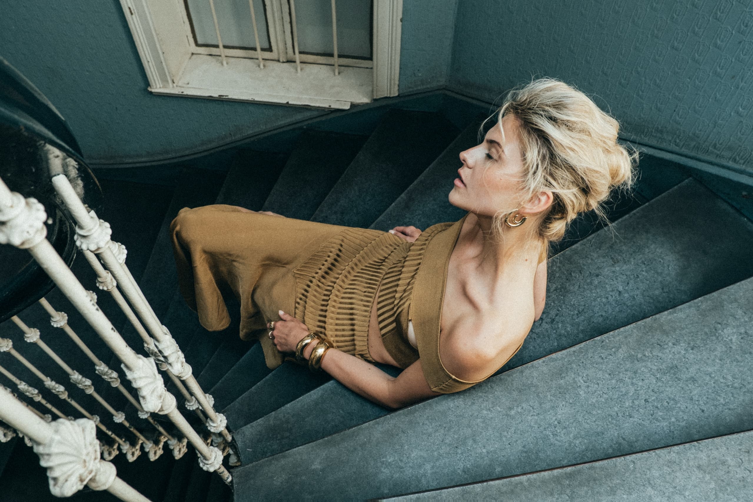 Stylish woman in elegant attire sitting on vintage stairway.