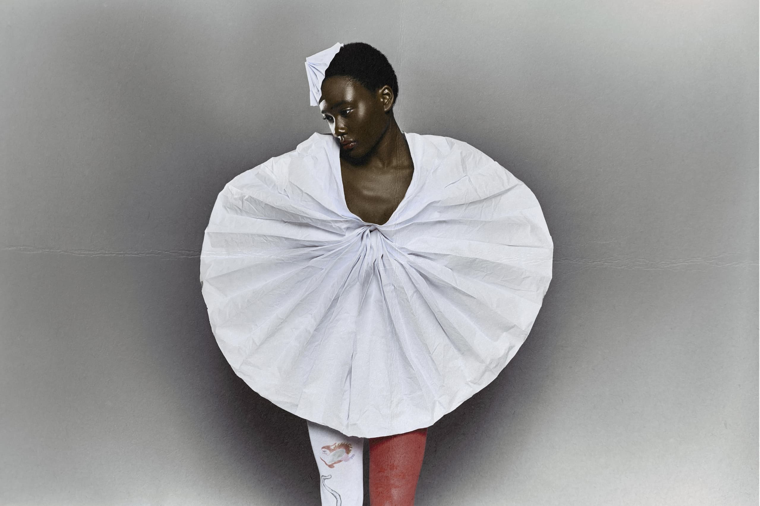 Model in a unique white paper dress with grey background. Fashion art photography.