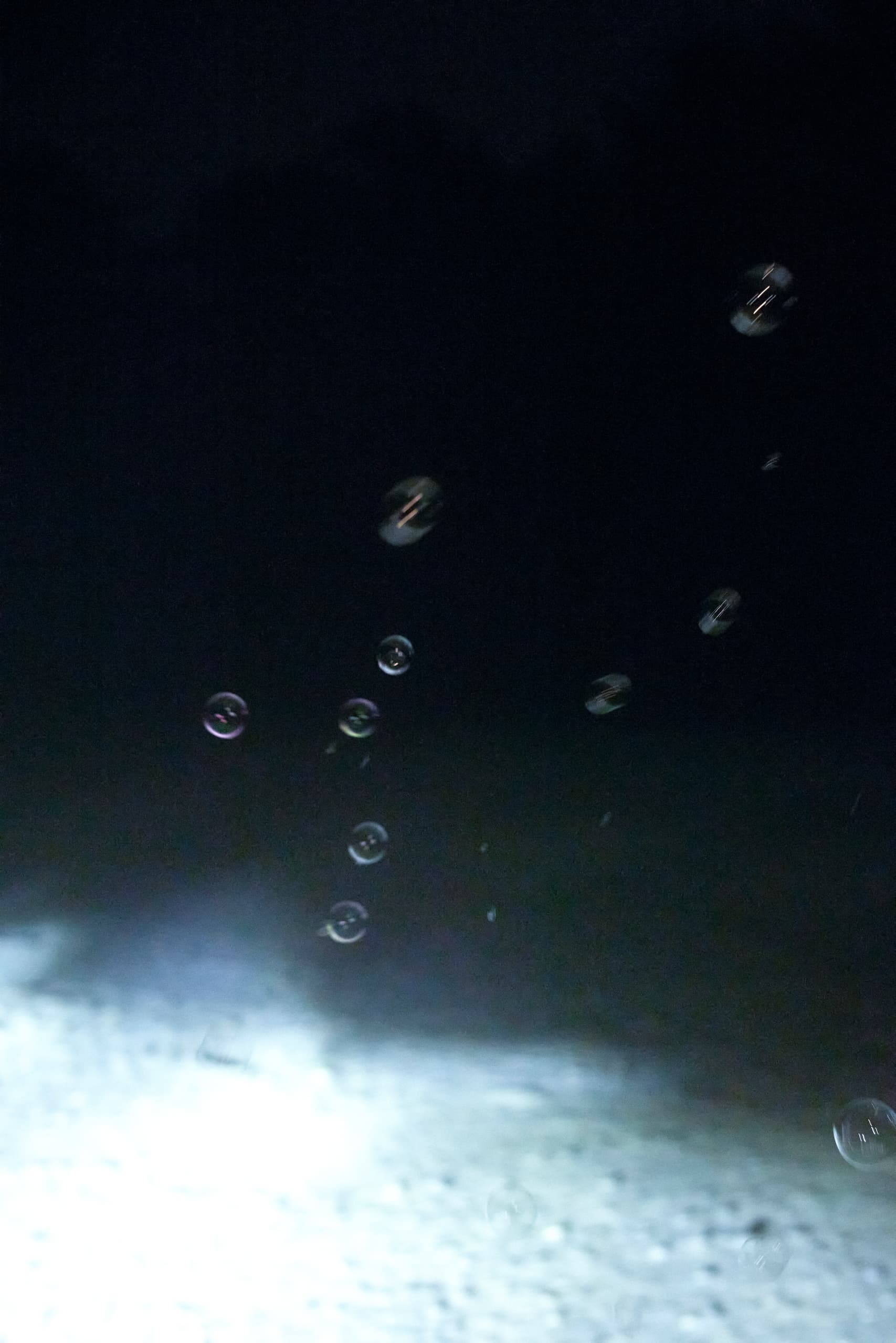 Bubbles illuminated at night against a dark background, creating an ethereal atmosphere.