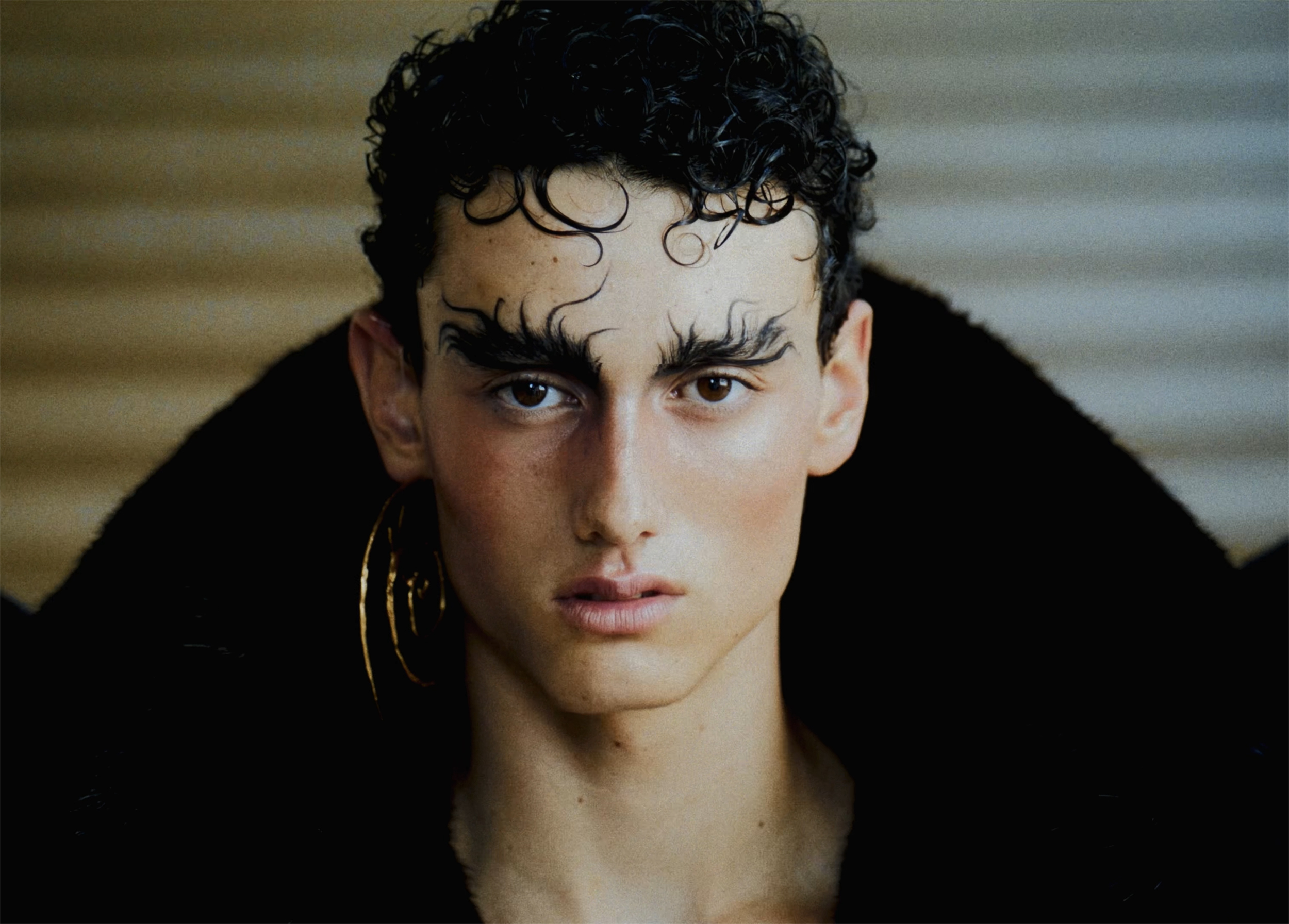 Person with artful eyebrows wearing black coat; close-up portrait.