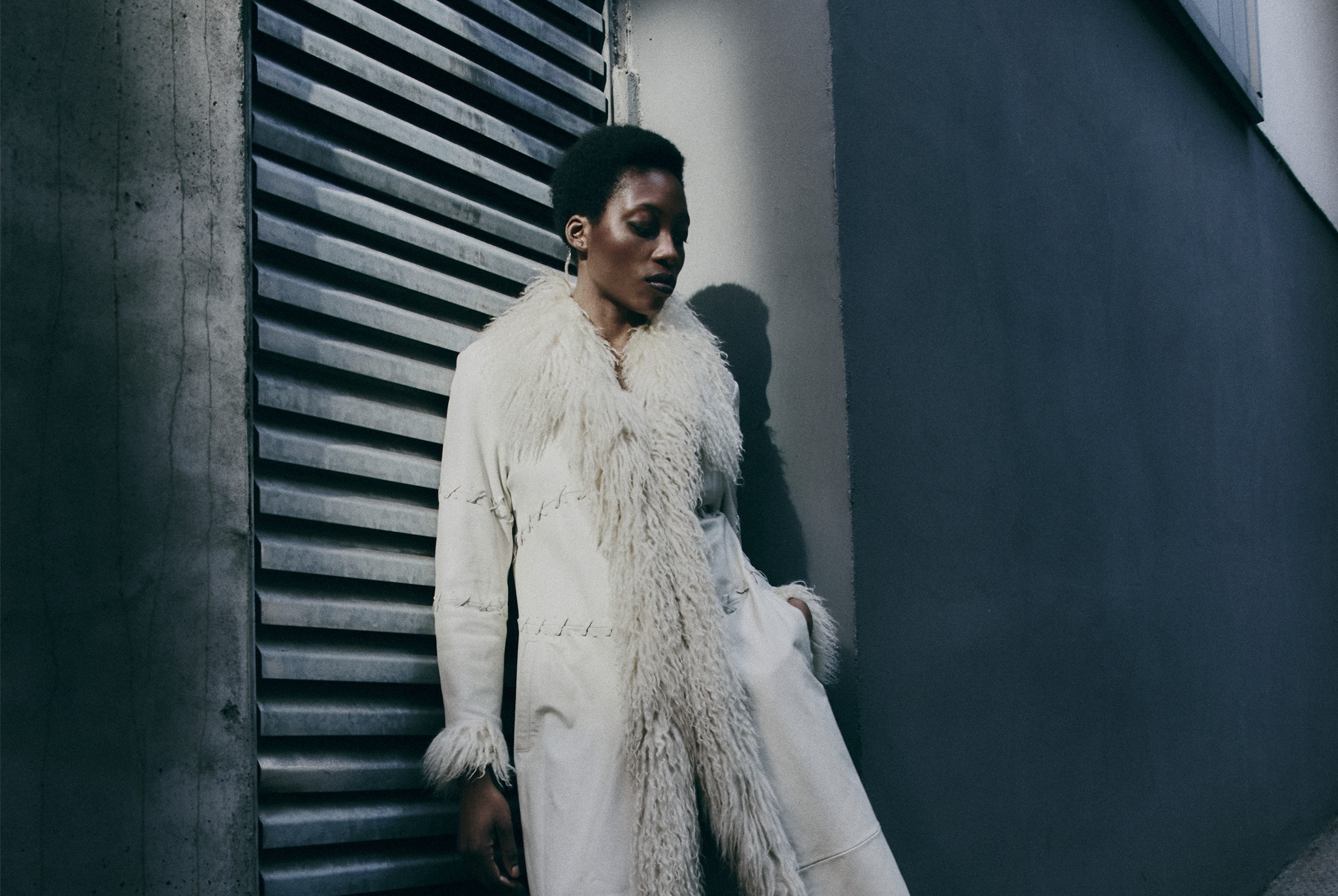Person in urban setting wearing a stylish white coat with fur details.